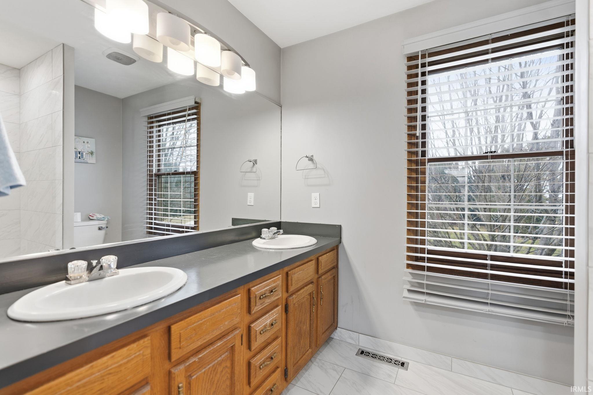 Full bathroom with double vanity and baseboards