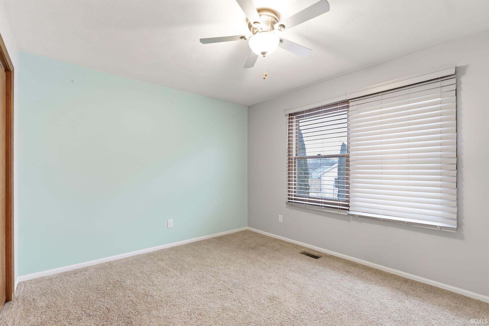 Carpeted spare room featuring baseboards and ceiling fan