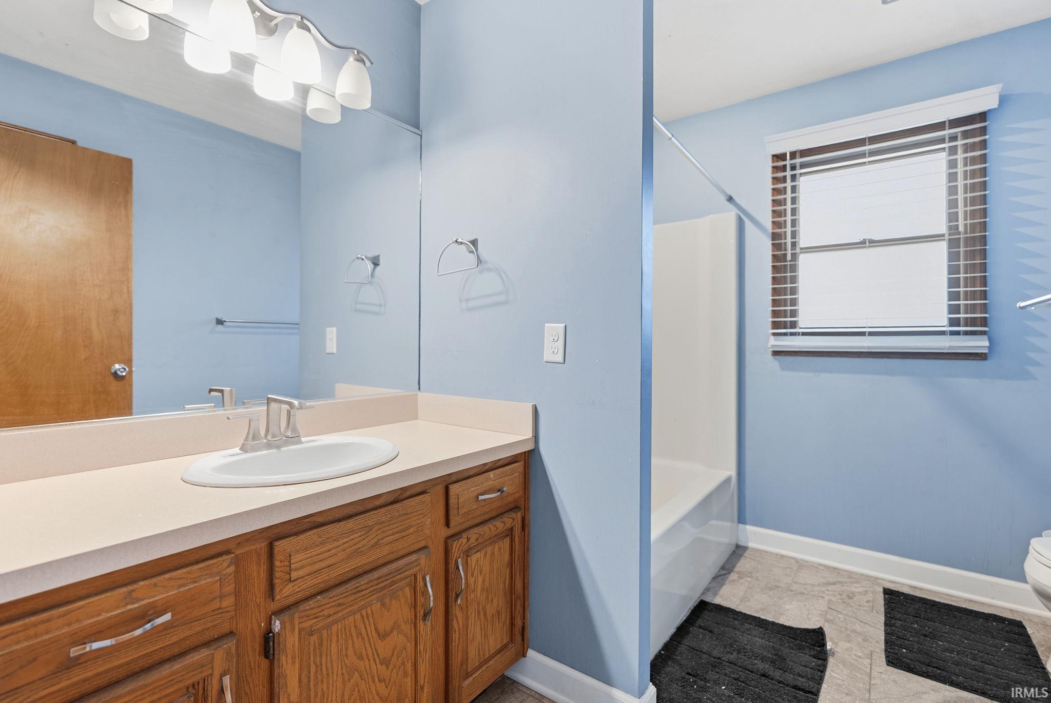 Full bath featuring vanity, light tile patterned floors, and bathtub / shower combination