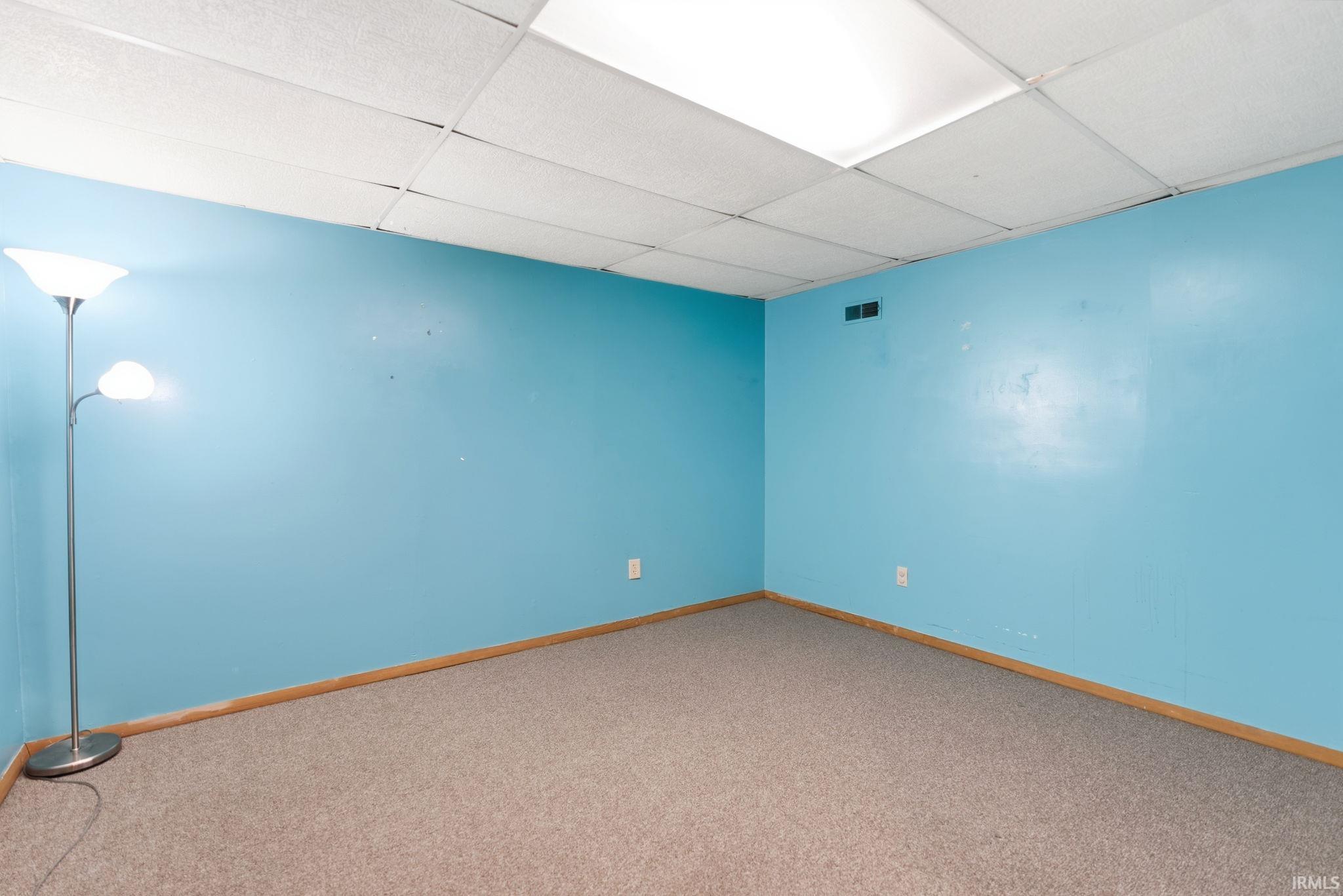 Carpeted spare room with a drop ceiling and baseboards