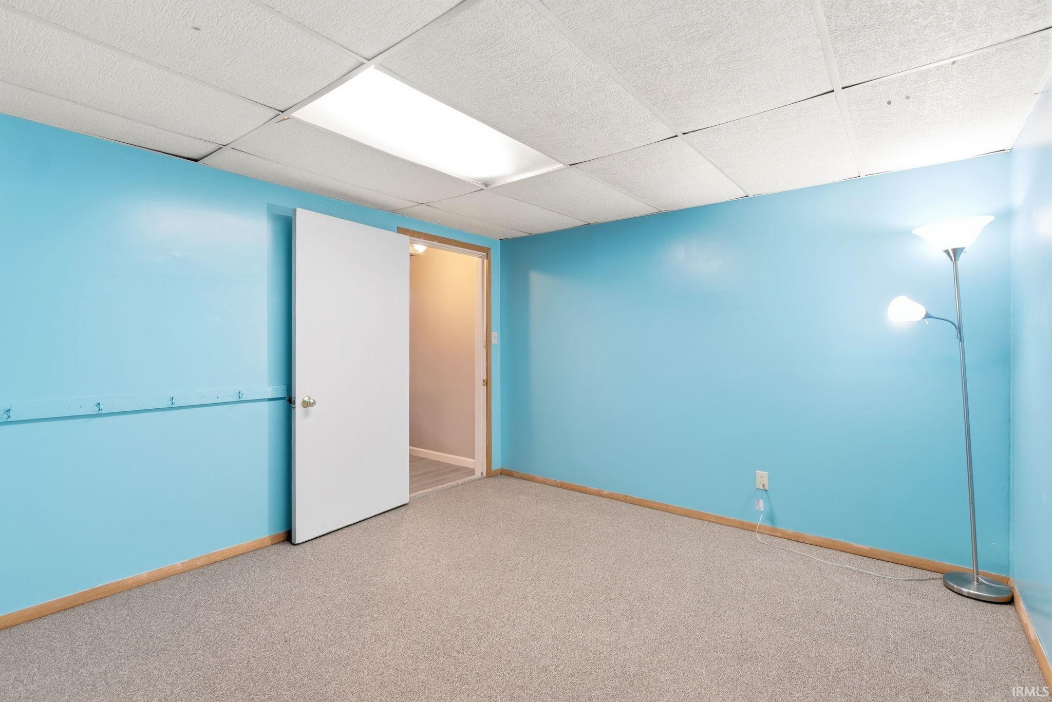 Carpeted spare room with baseboards and a paneled ceiling