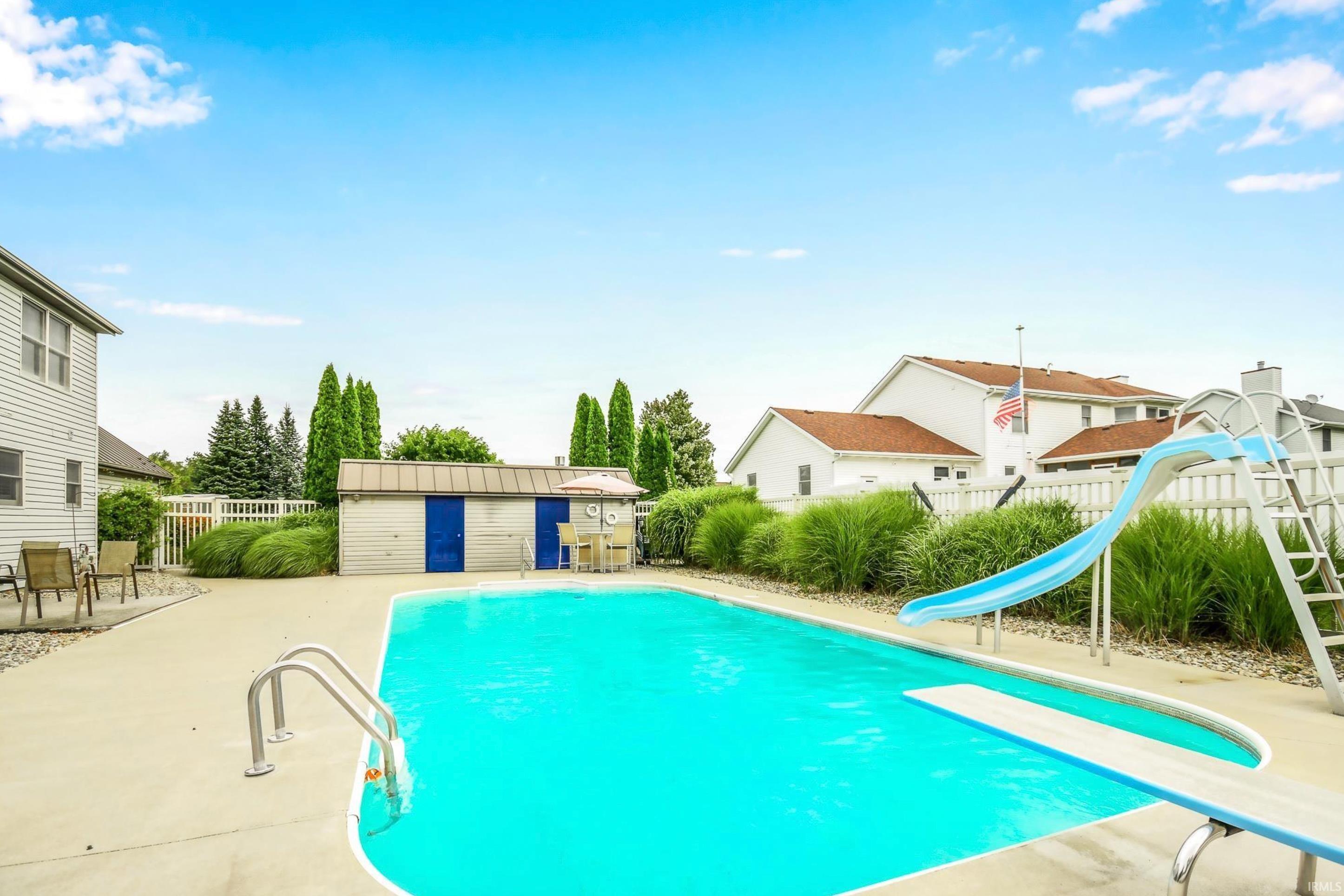 View of swimming pool featuring a water slide, a diving board, patio surround, and an outbuilding