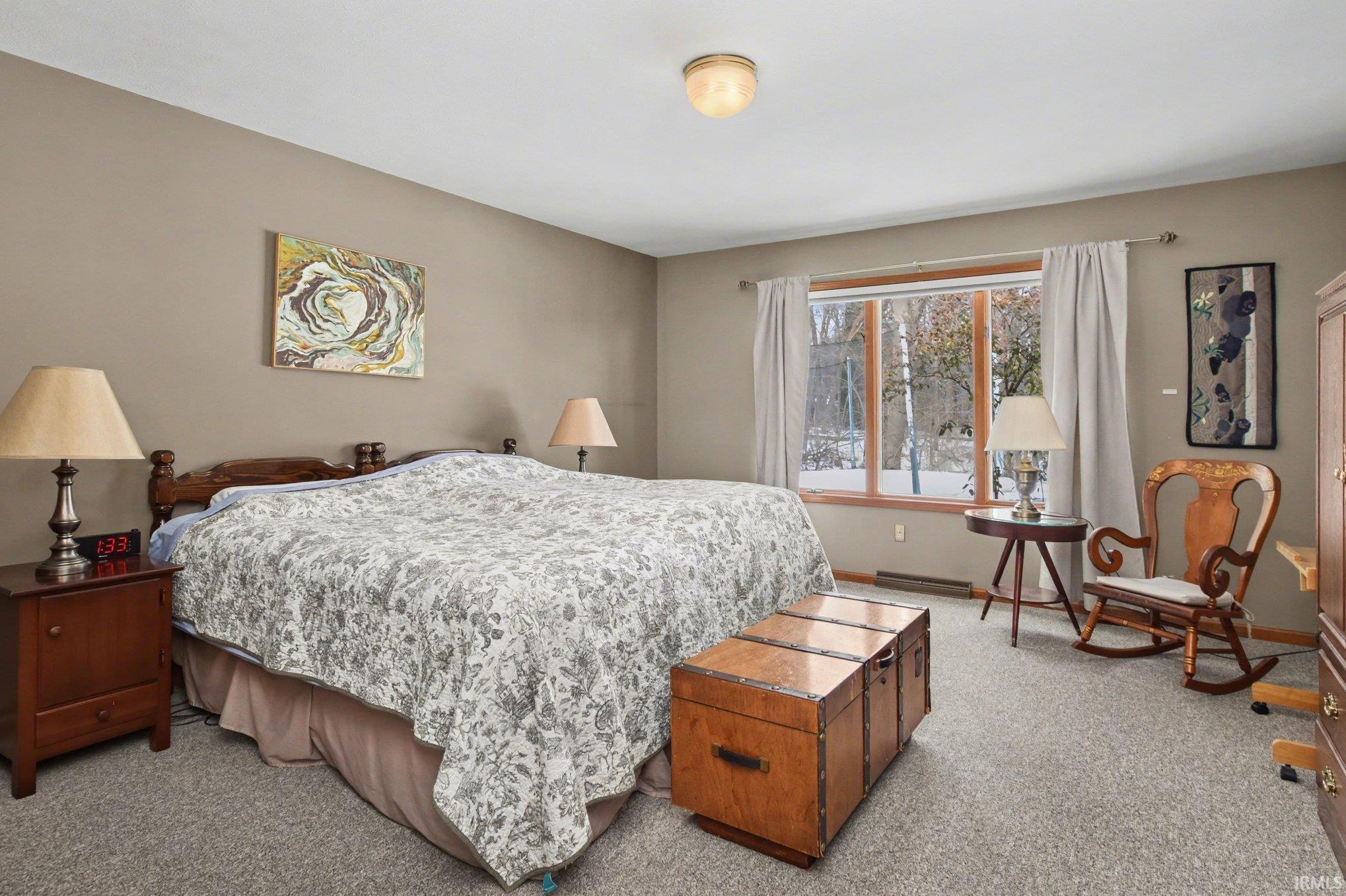 Bedroom with light carpet and a baseboard heating unit