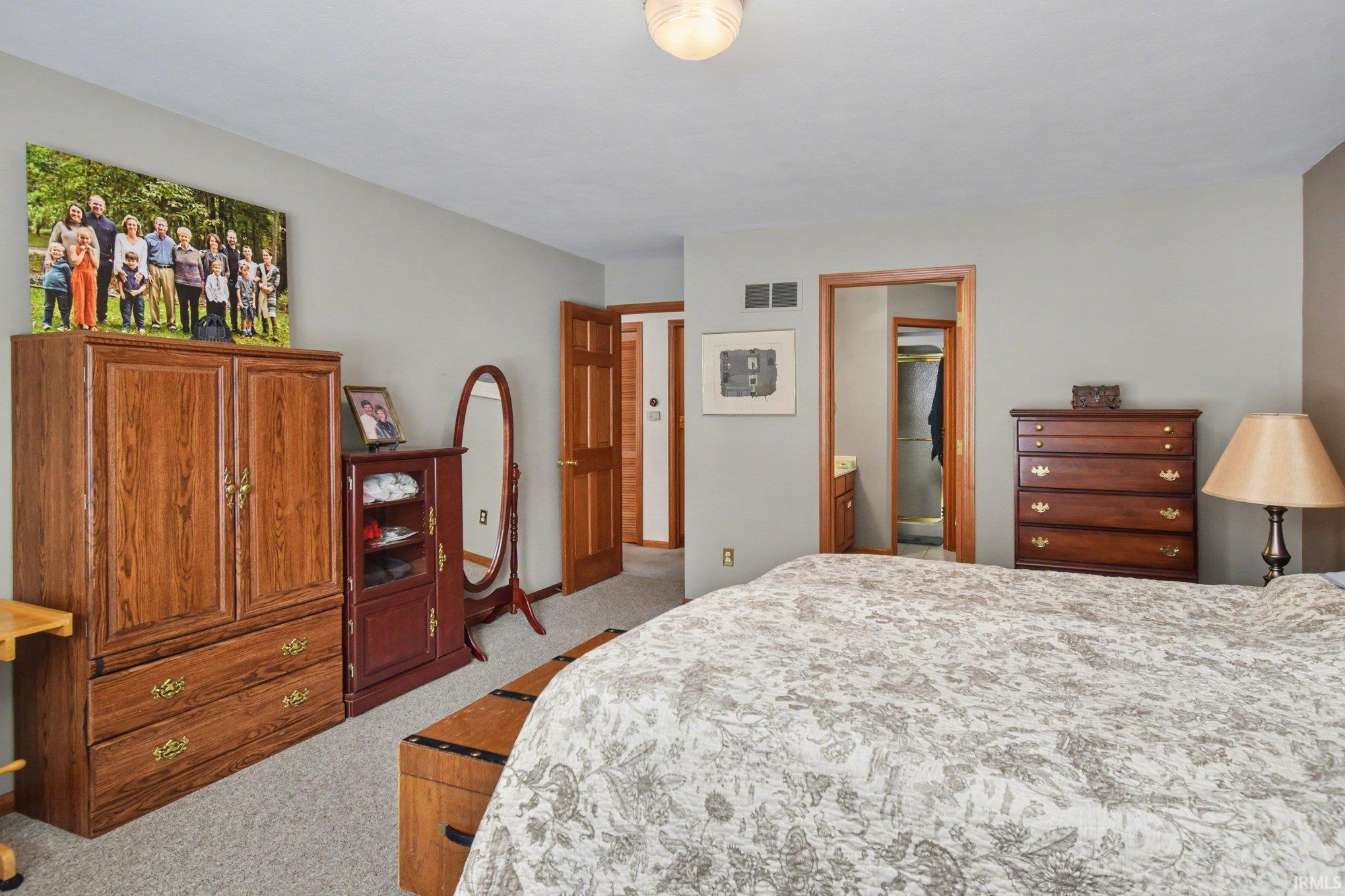 Bedroom featuring light colored carpet and ensuite bath