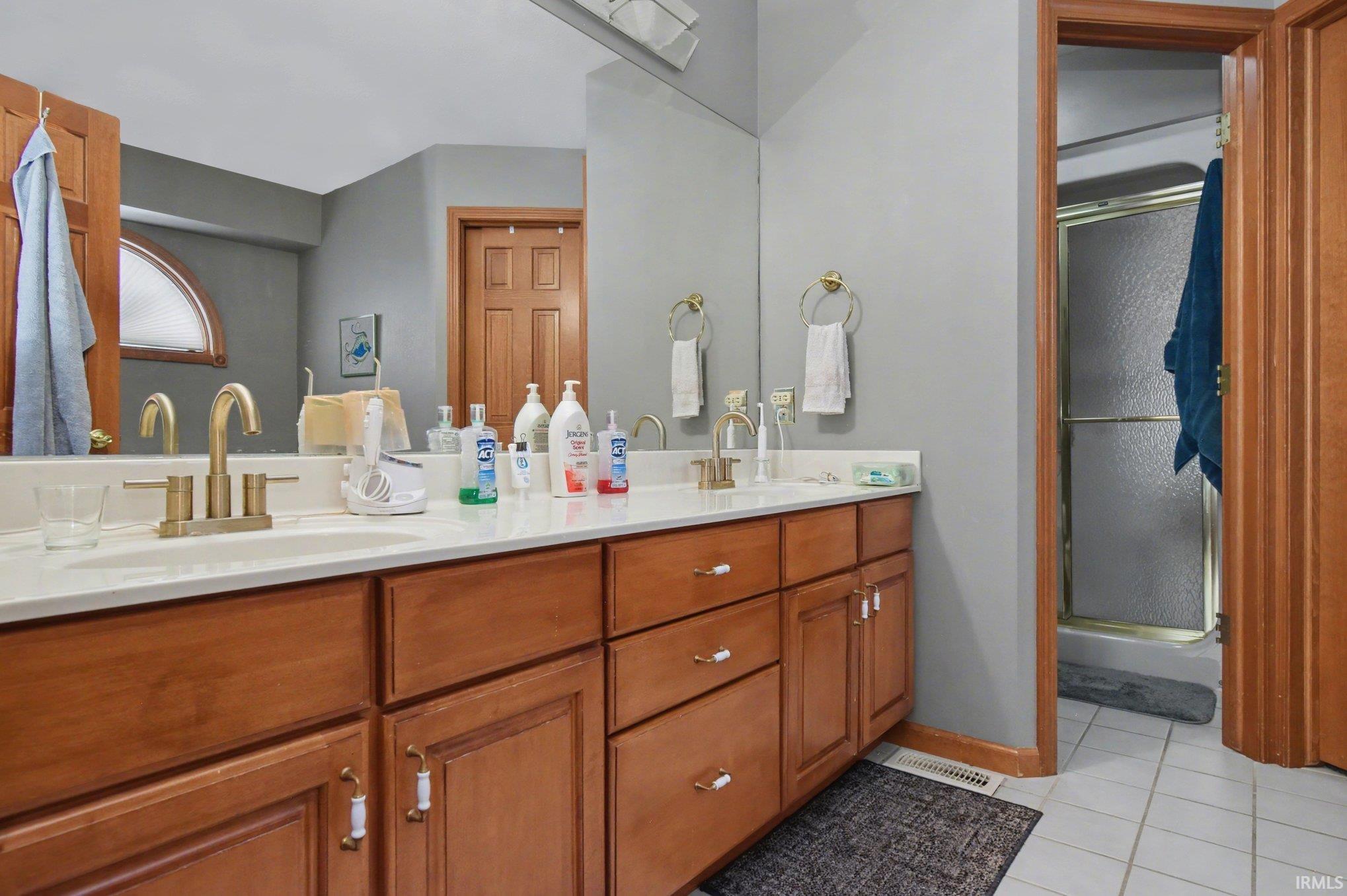 Full bathroom featuring double vanity, a shower stall, and light tile patterned flooring