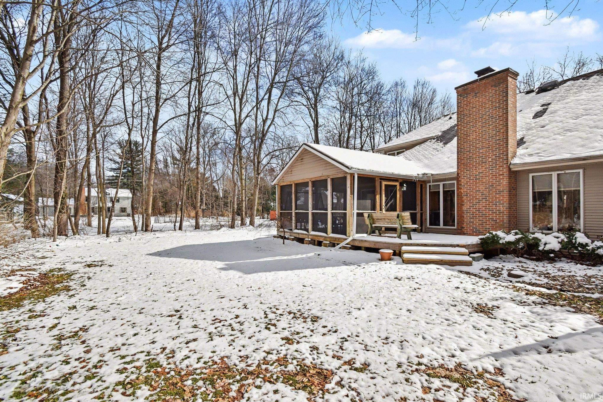 Snow covered house with a sunroom and a chimney