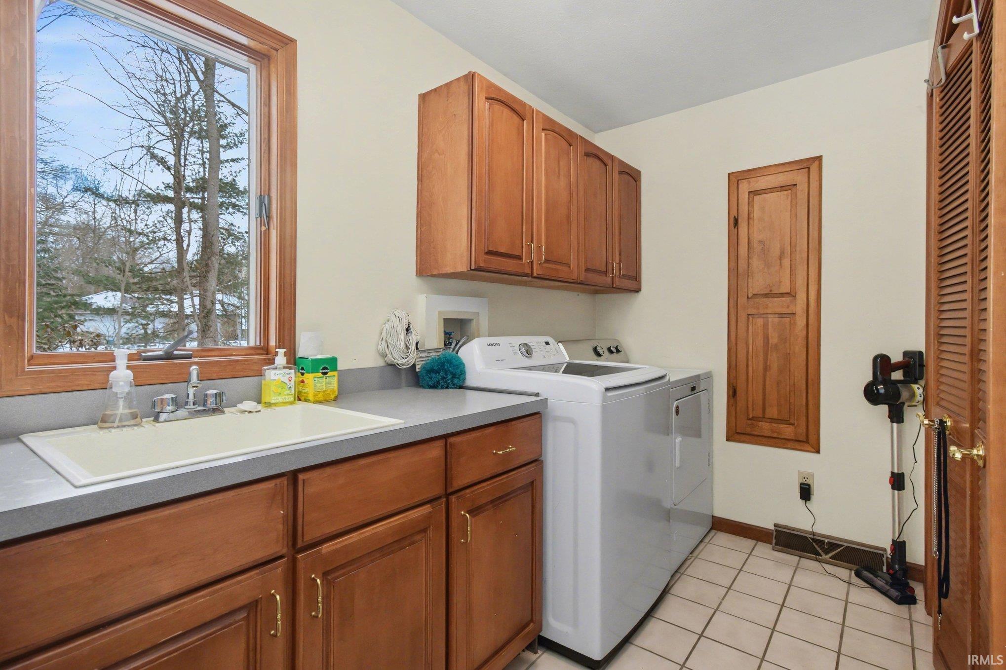 Laundry area featuring cabinet space, washer and dryer, and light tile patterned floors