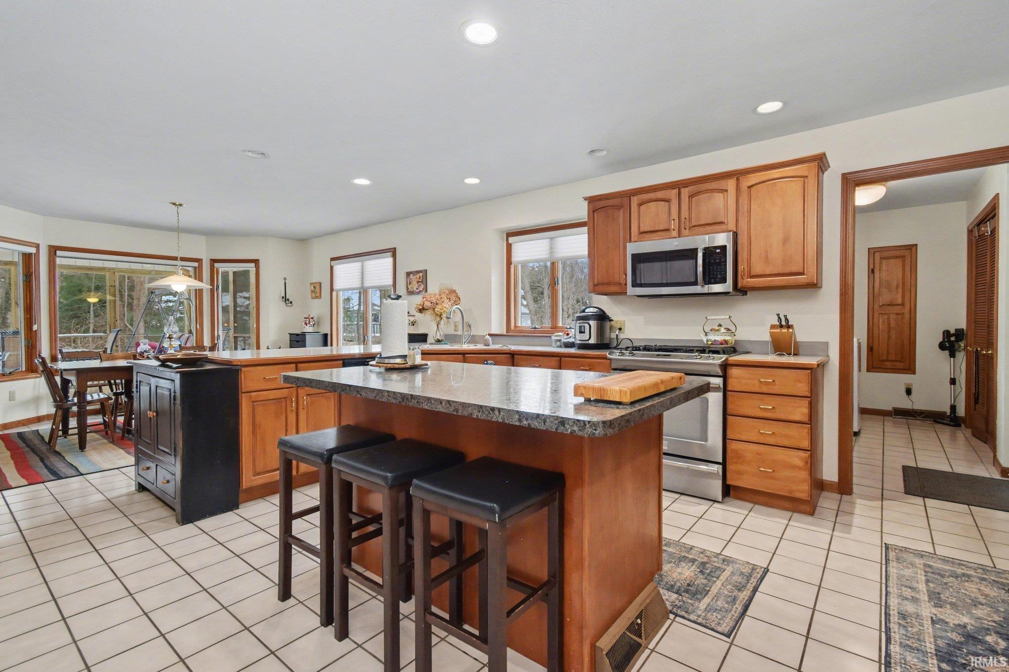 Kitchen featuring stainless steel appliances, a kitchen breakfast bar, a center island, pendant lighting, and a peninsula