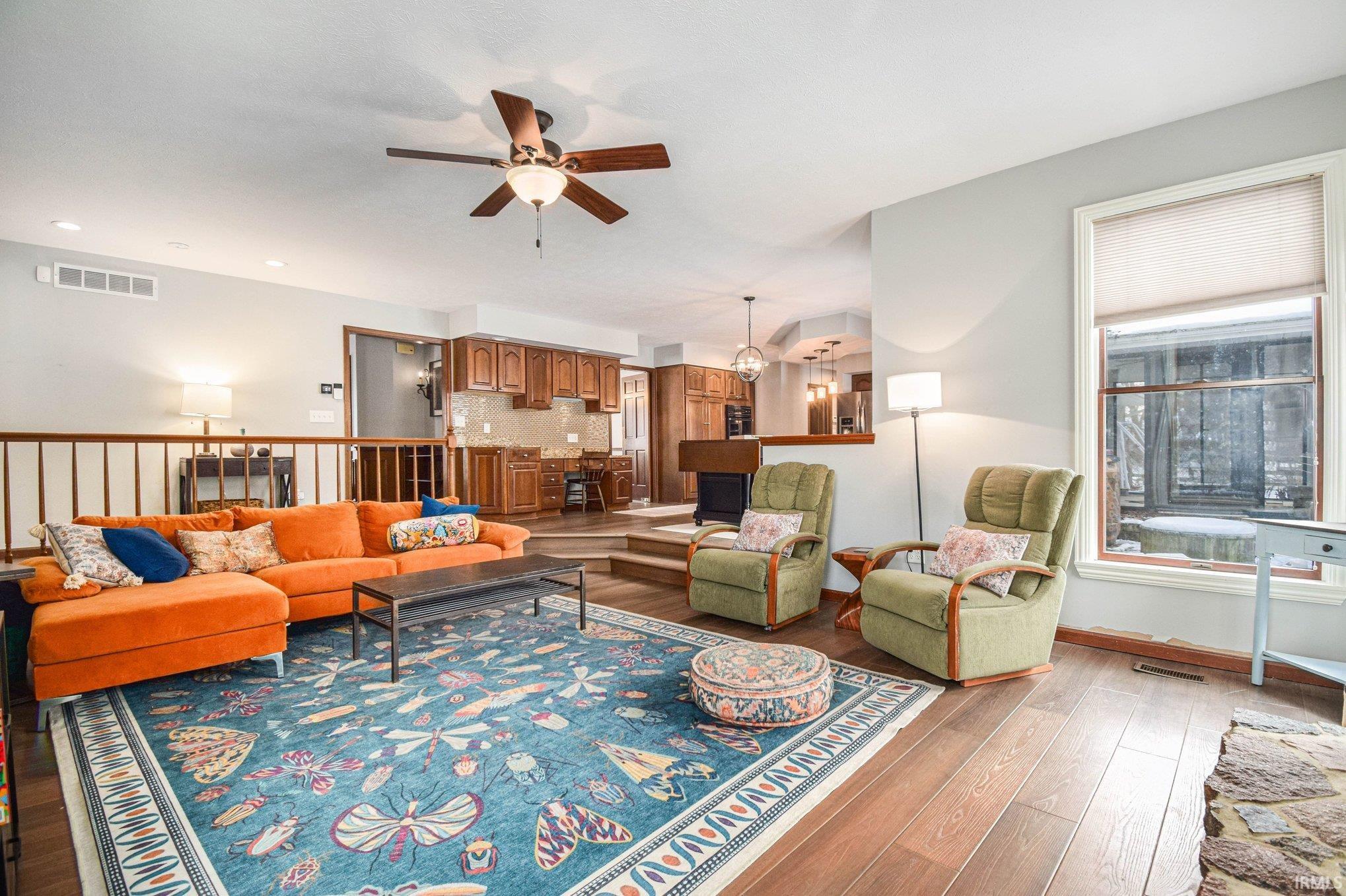 Living room with a ceiling fan and dark wood-style flooring