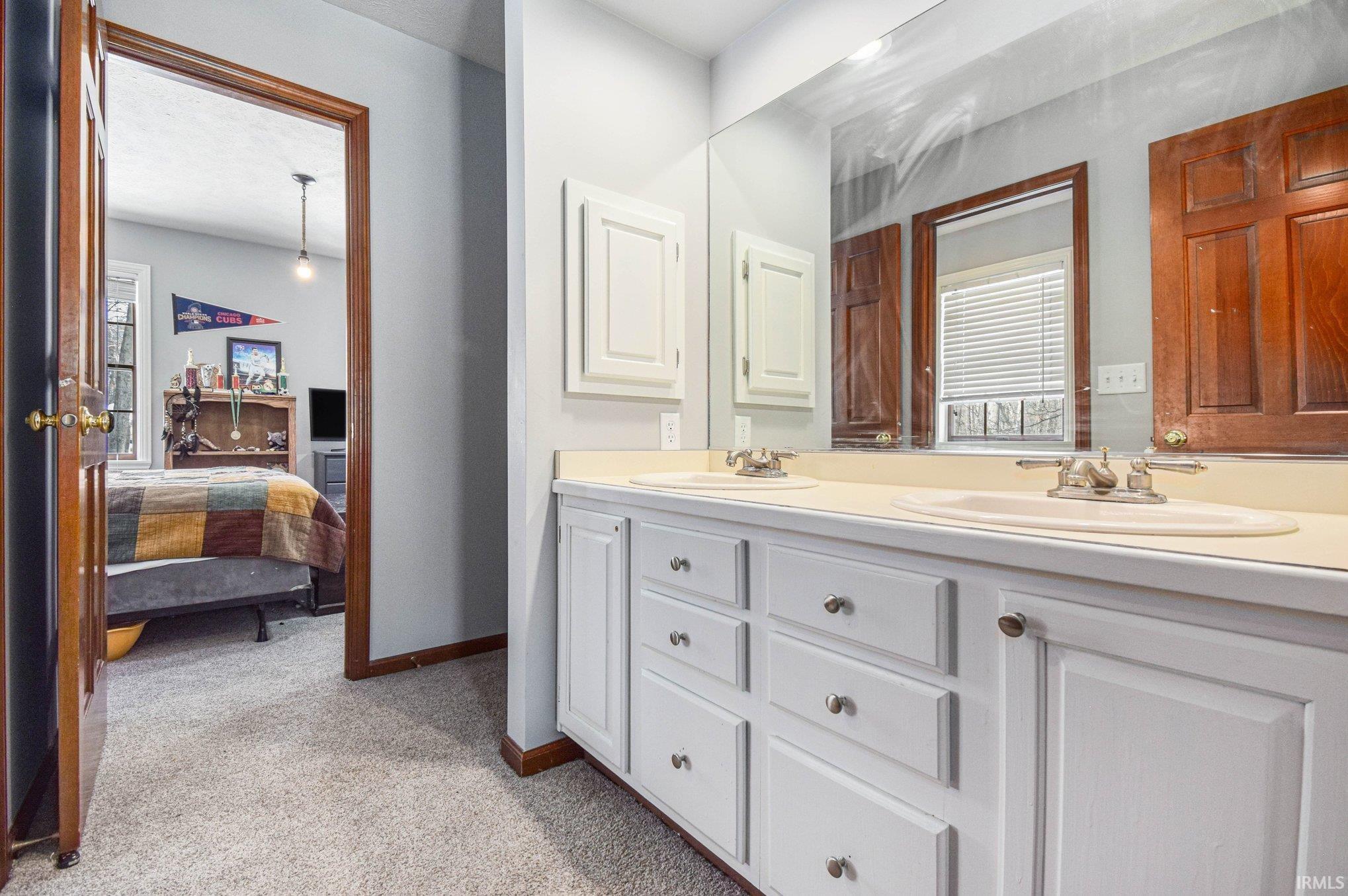 Ensuite bathroom featuring double vanity and light carpet