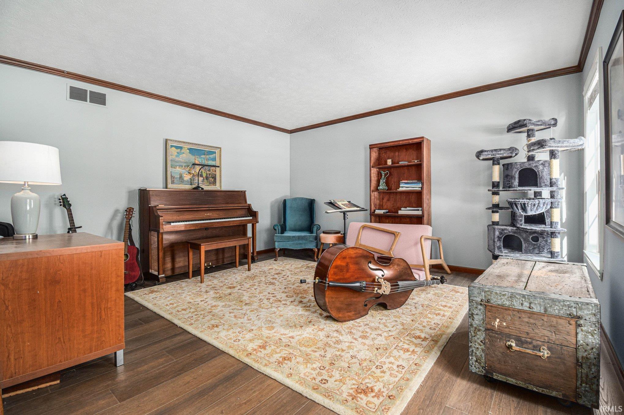Sitting room featuring dark wood finished floors, ornamental molding, and a textured ceiling