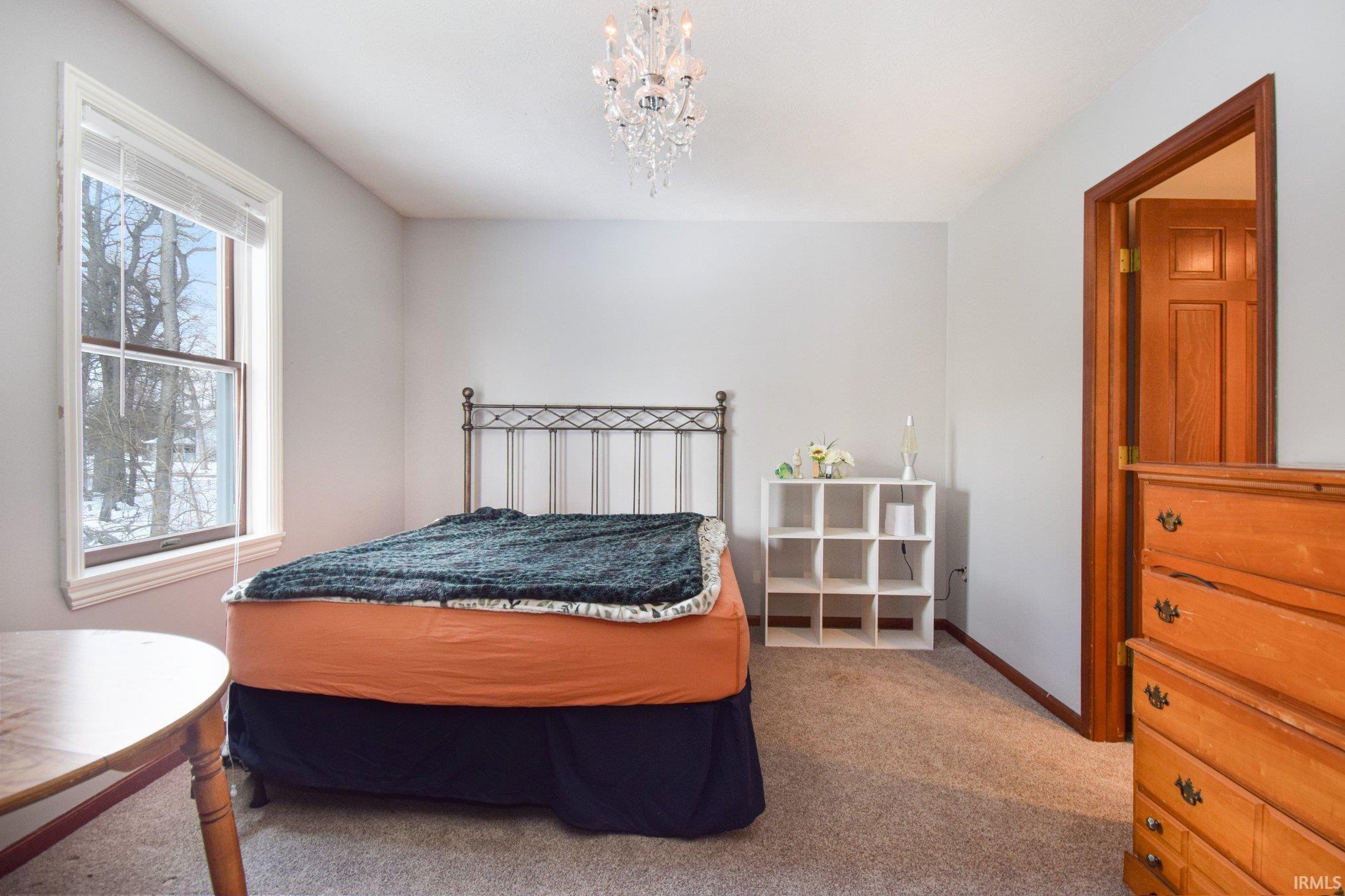 Bedroom featuring light colored carpet and hanging lights