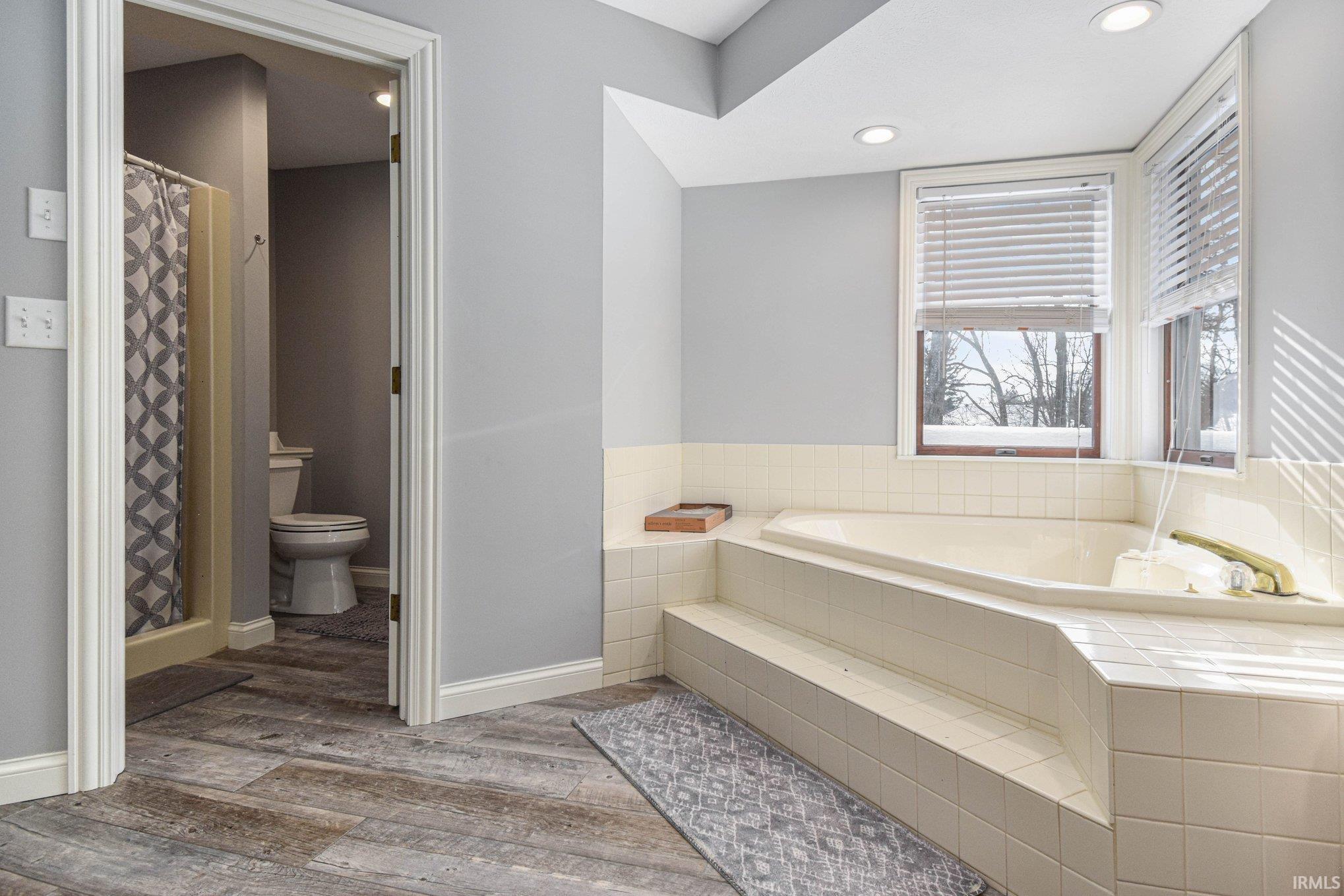 Full bathroom featuring a shower stall, recessed lighting, light wood-style flooring, and a bath