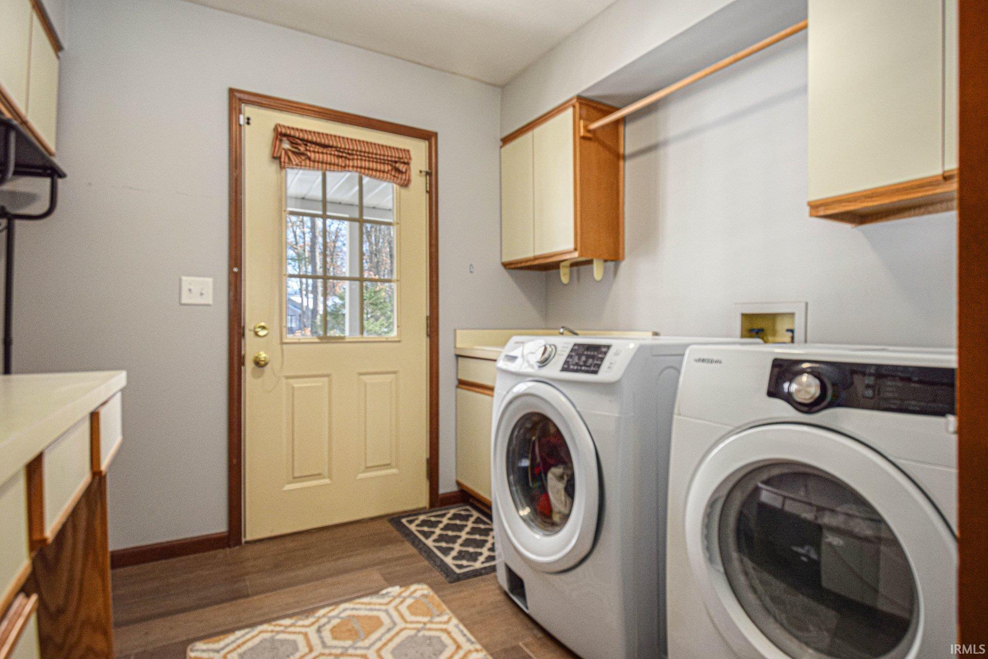 Laundry area with separate washer and dryer, dark wood-style flooring, and cabinet space