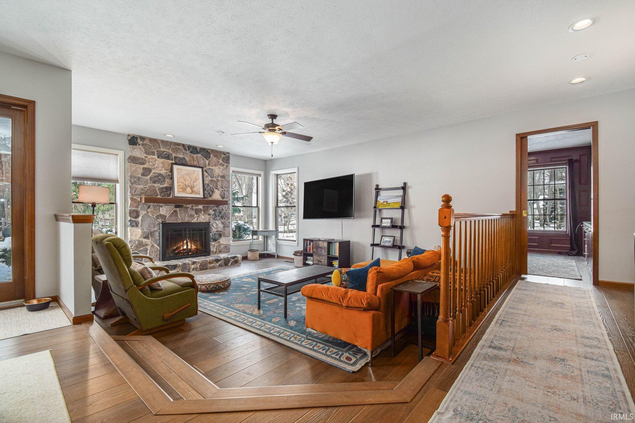 Living room with hardwood / wood-style floors, a fireplace, ceiling fan, recessed lighting, and a textured ceiling