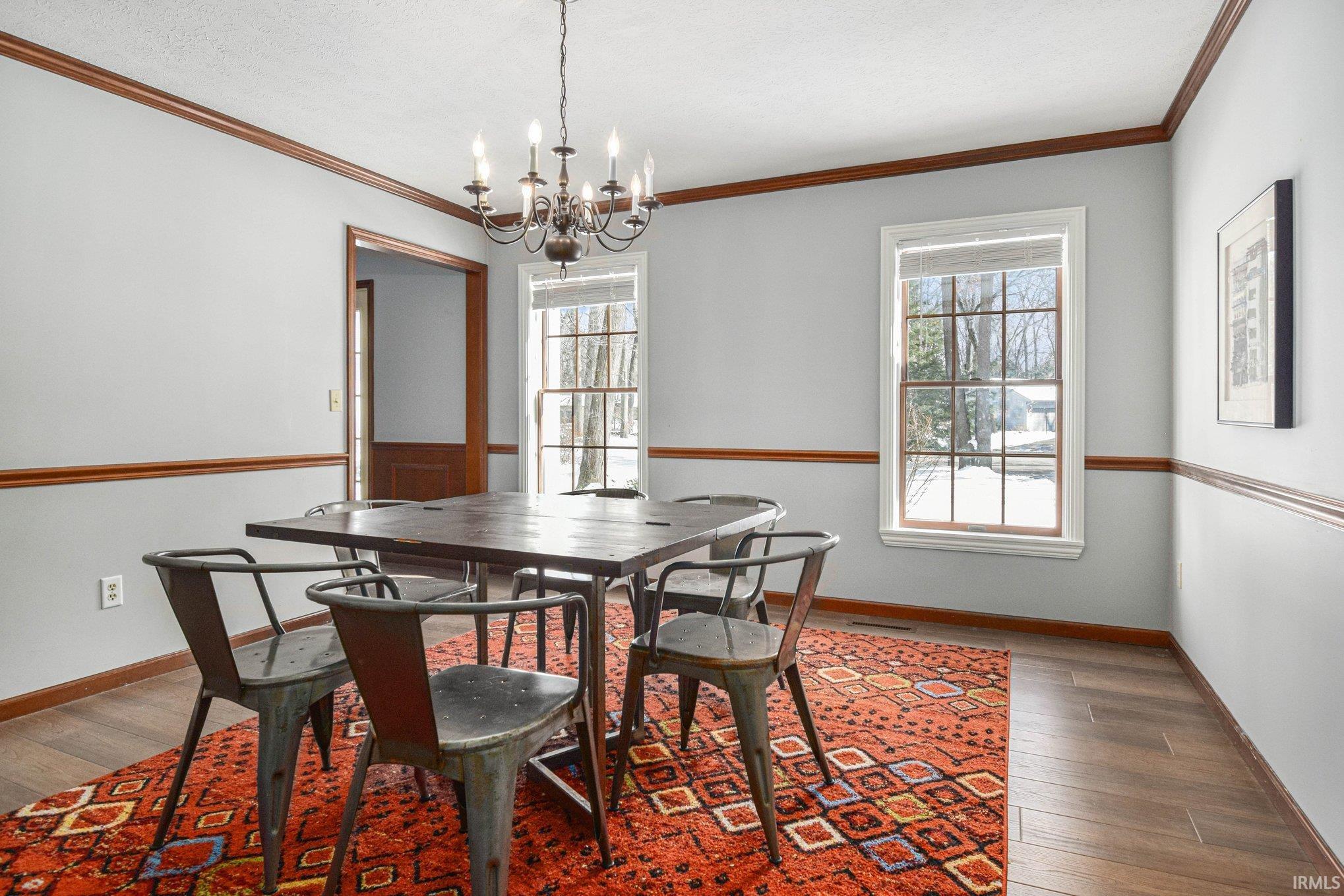 Dining area with ornamental molding, wood-type flooring, and suspended lighting
