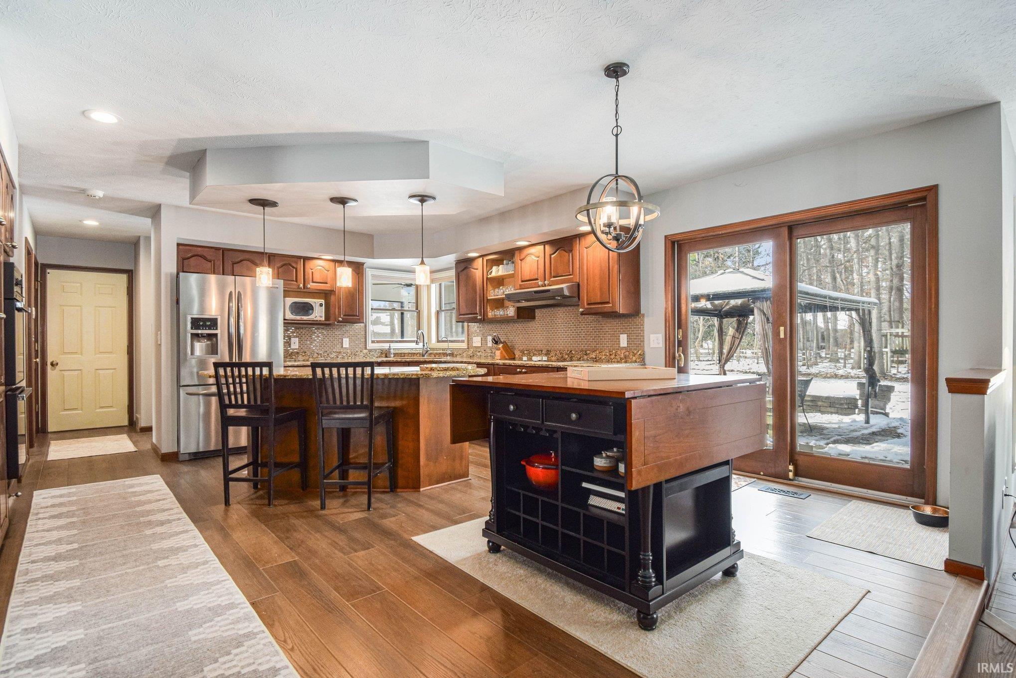 Kitchen featuring a center island, wood finish cabinetry, stainless steel fridge, and hanging light fixtures