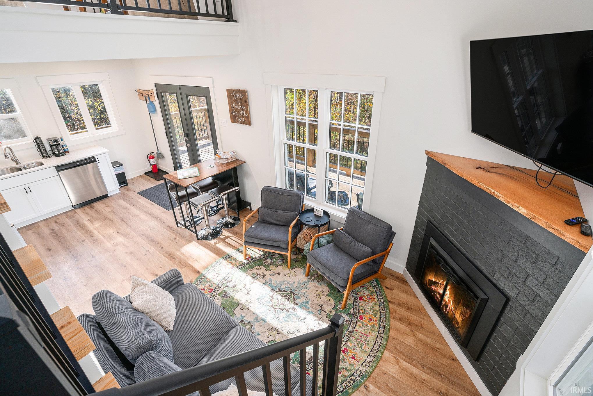 Living room featuring a glass covered fireplace, light wood-style flooring, and a high ceiling