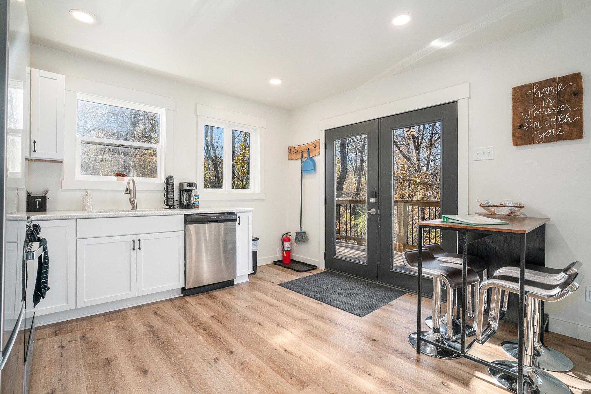 Kitchen featuring french doors, white cabinetry, dishwasher, light wood finished floors, and recessed lighting