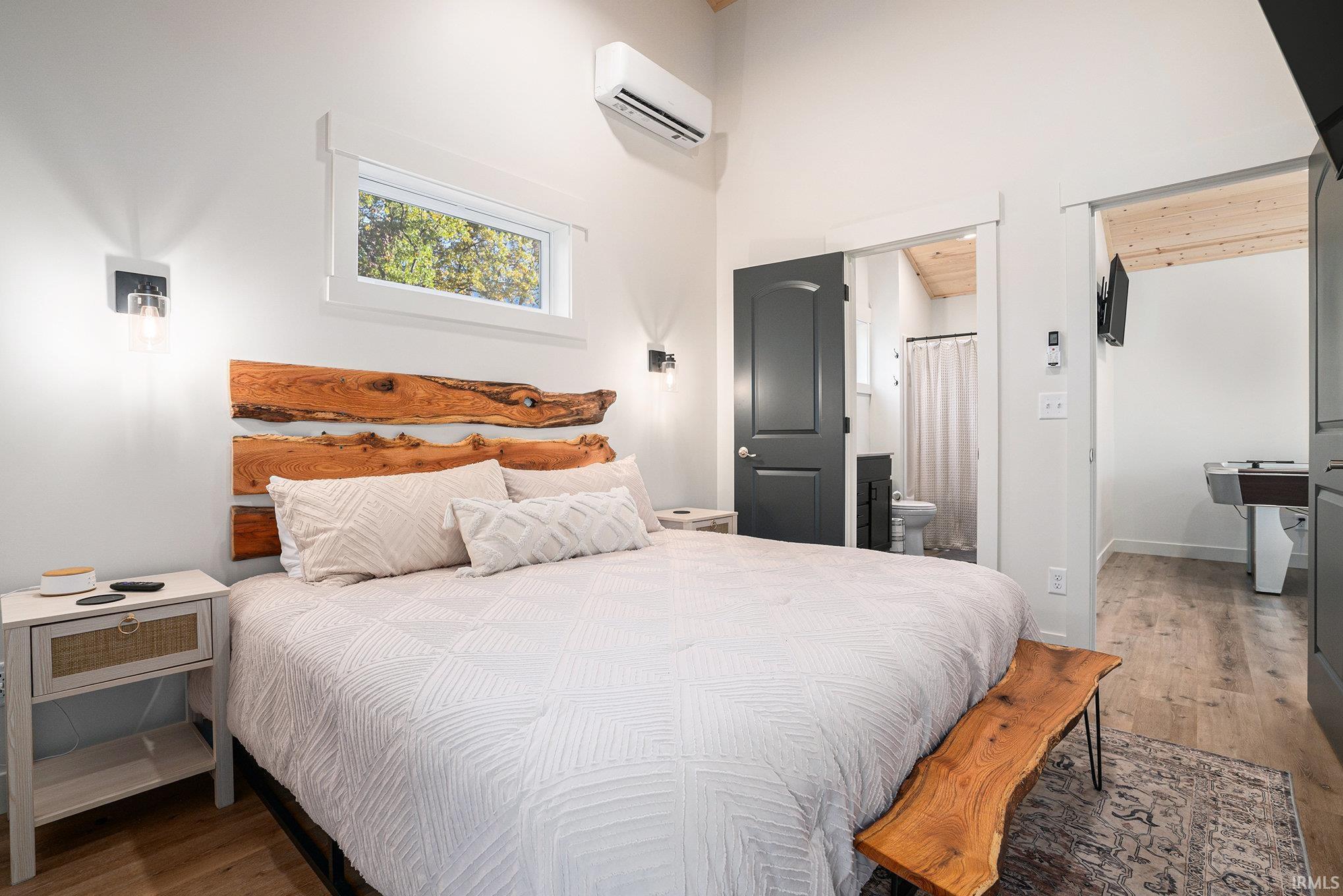 Bedroom with wood finished floors, connected bathroom, and a high ceiling