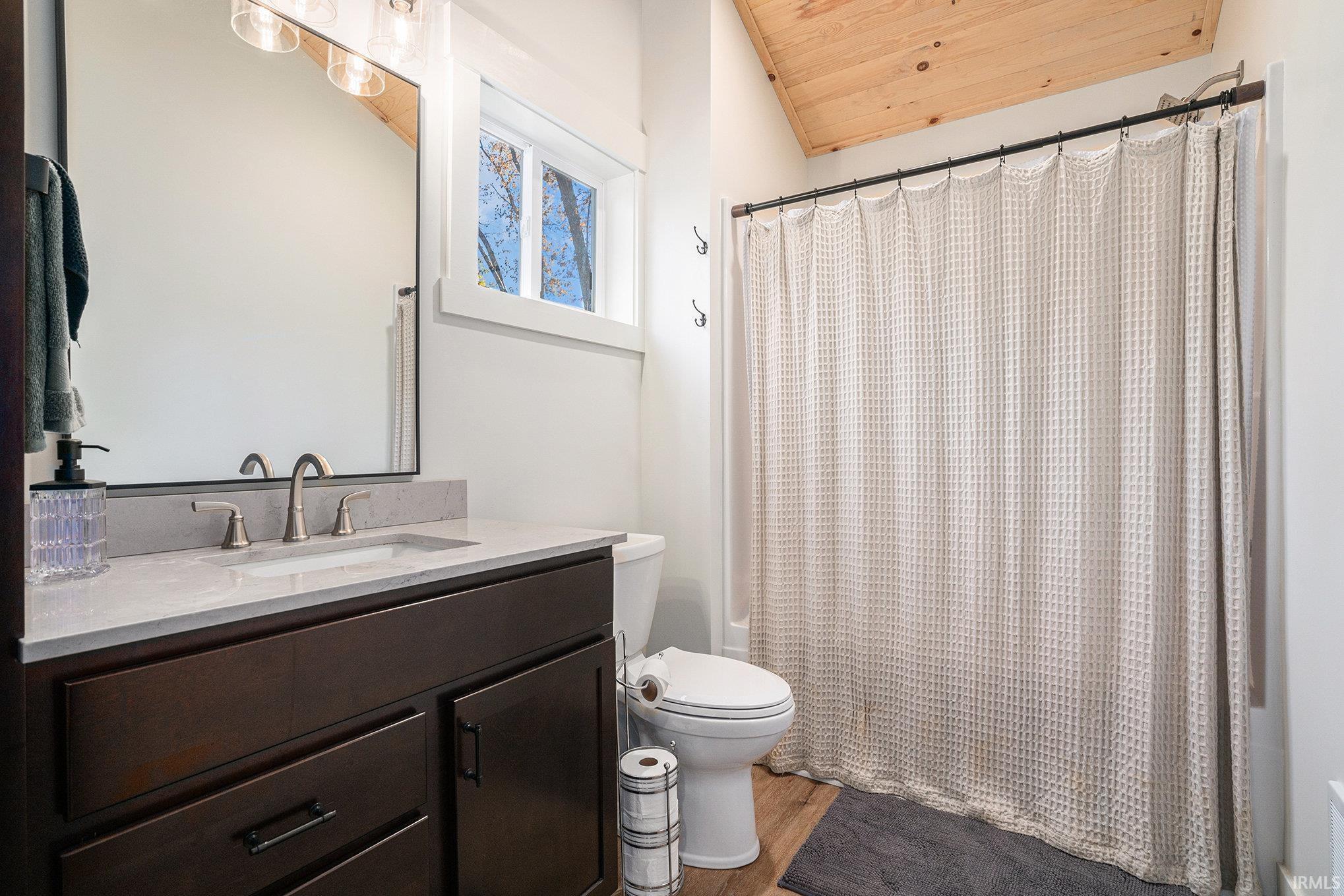 Bathroom featuring vanity, shower / tub combo with curtain, a vaulted wood ceiling, and light wood finished floors