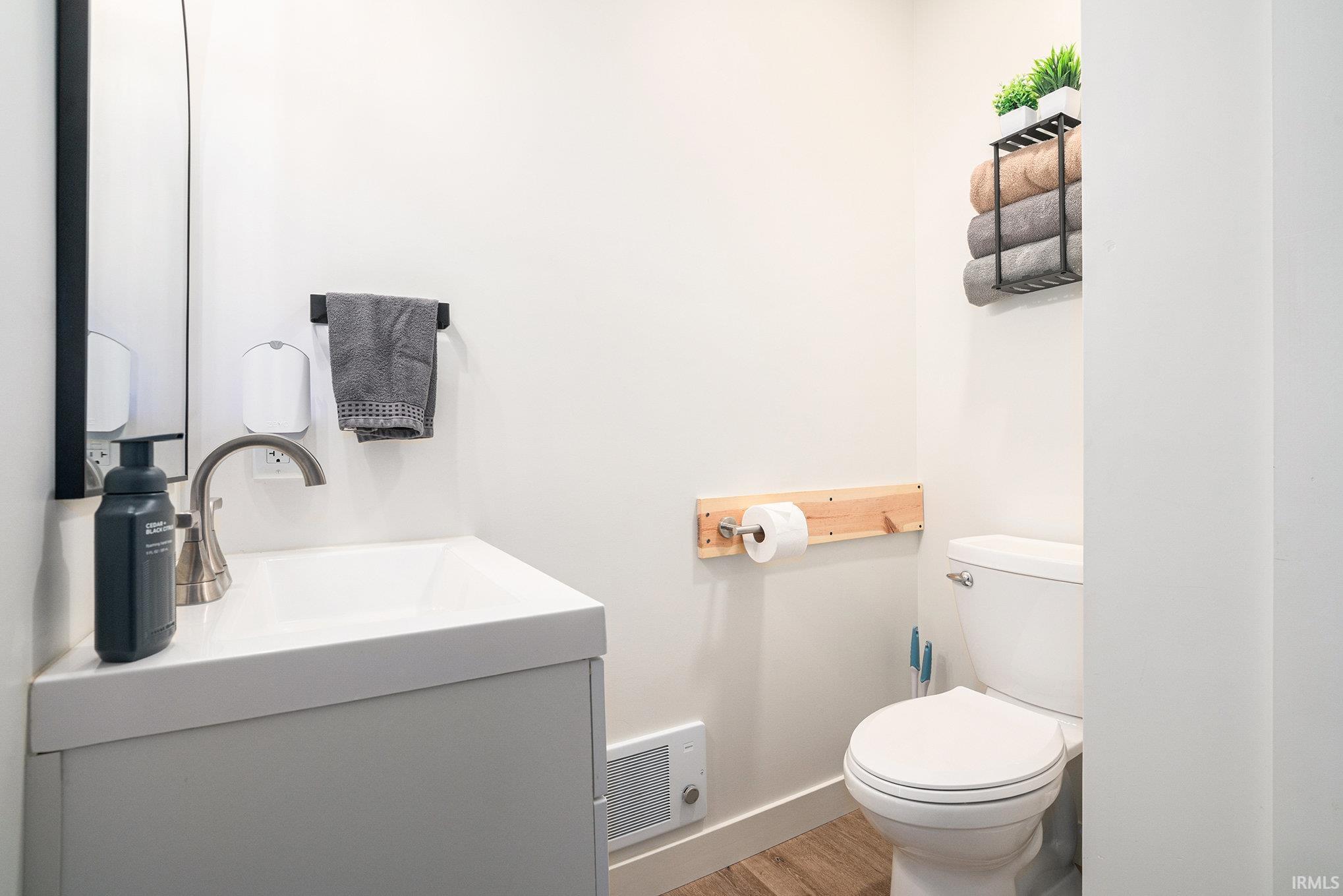 Half bath featuring vanity, light wood-style flooring, and heating unit