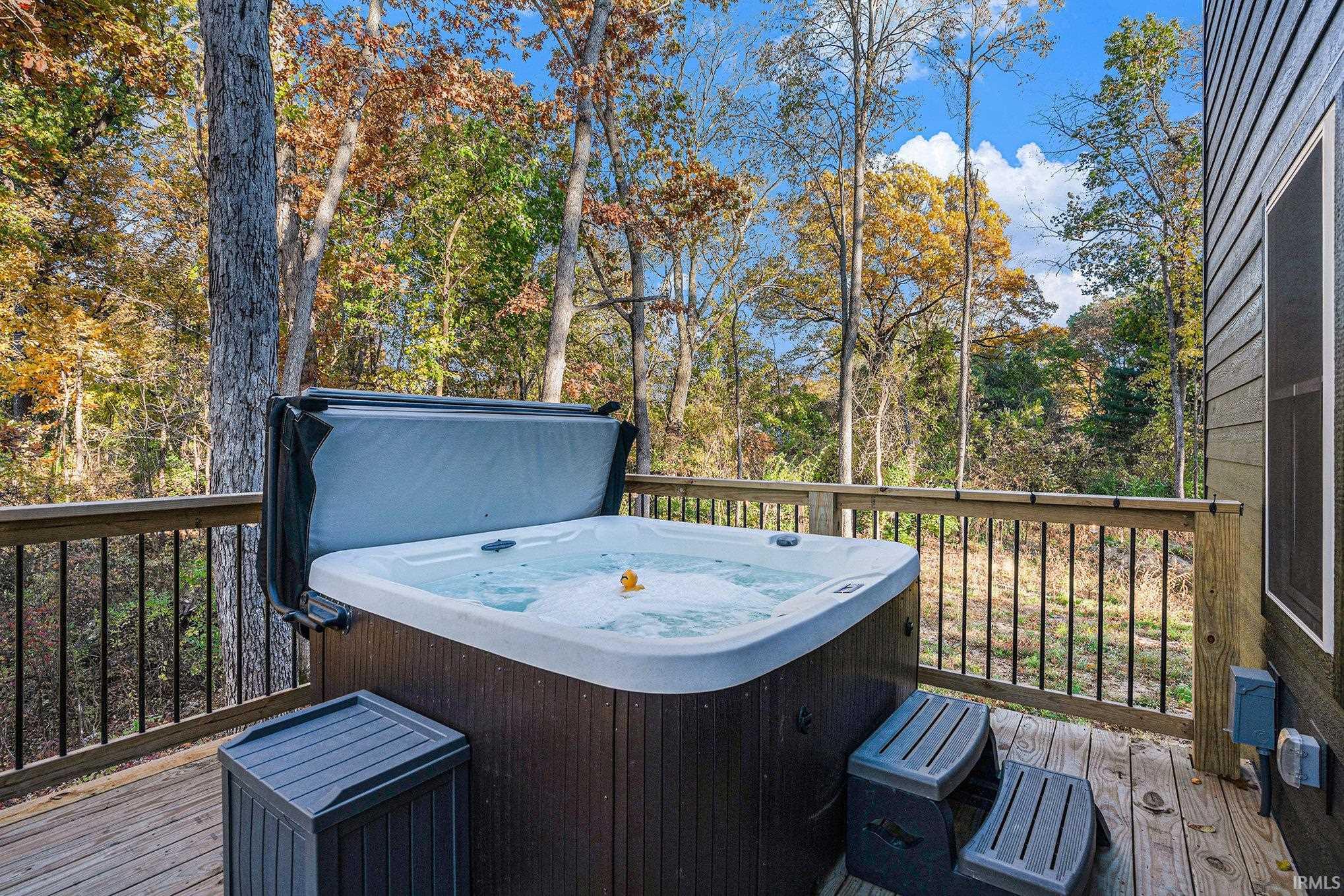 Wooden deck featuring a hot tub and view of wooded area