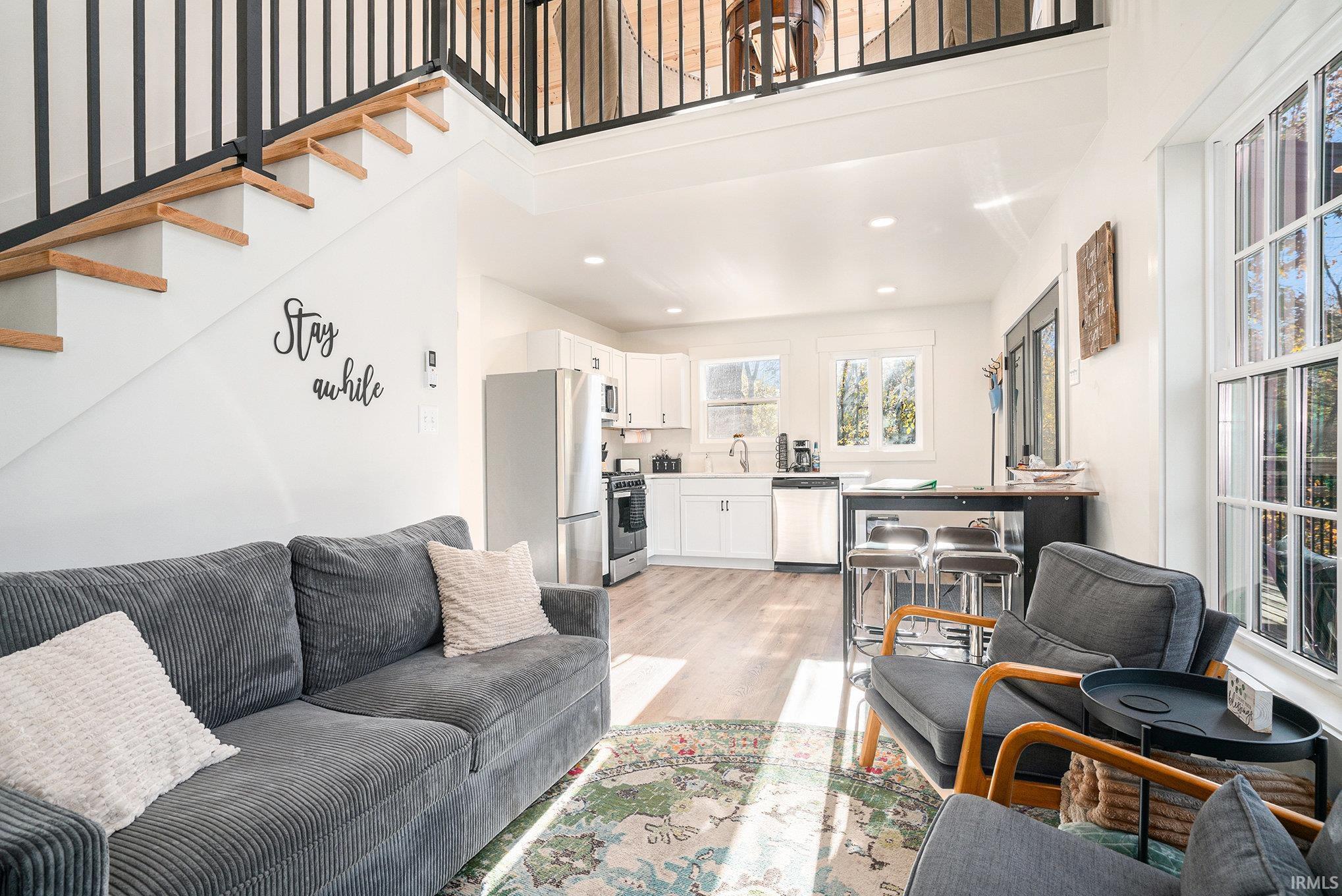 Living room with light wood-type flooring, a high ceiling, and recessed lighting