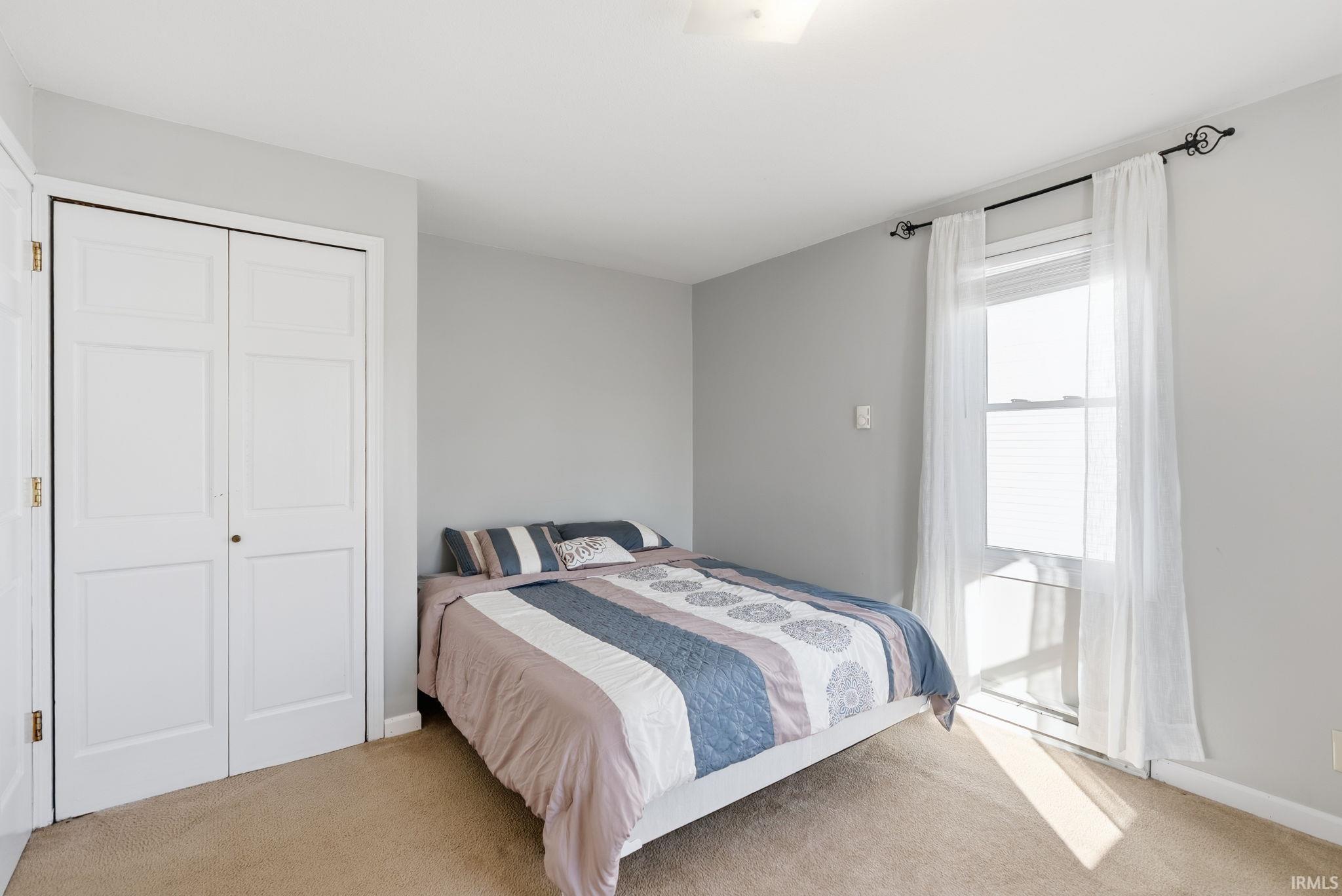 Bedroom with light carpet and a closet