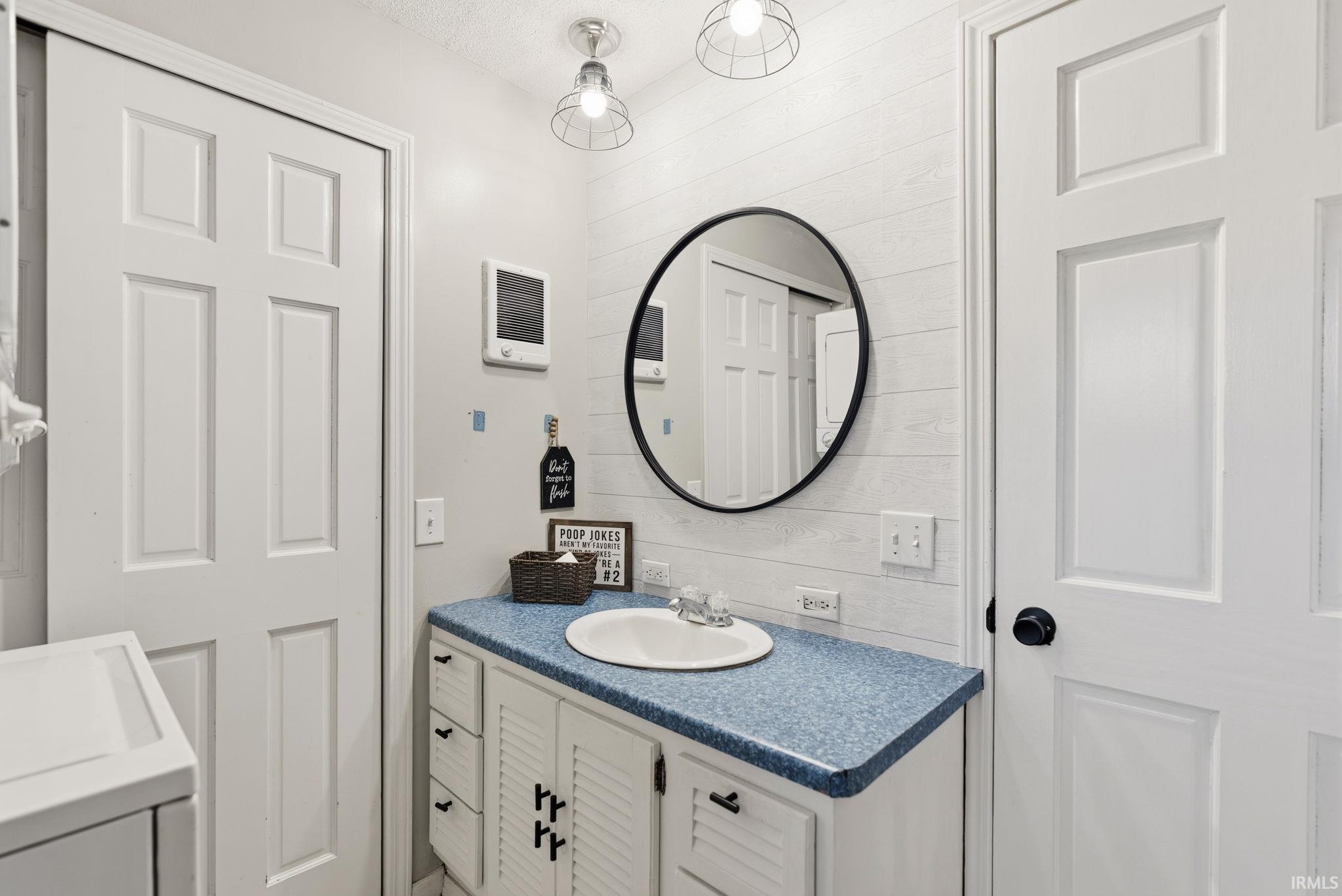 Bathroom featuring vanity, wooden walls, and washer / clothes dryer