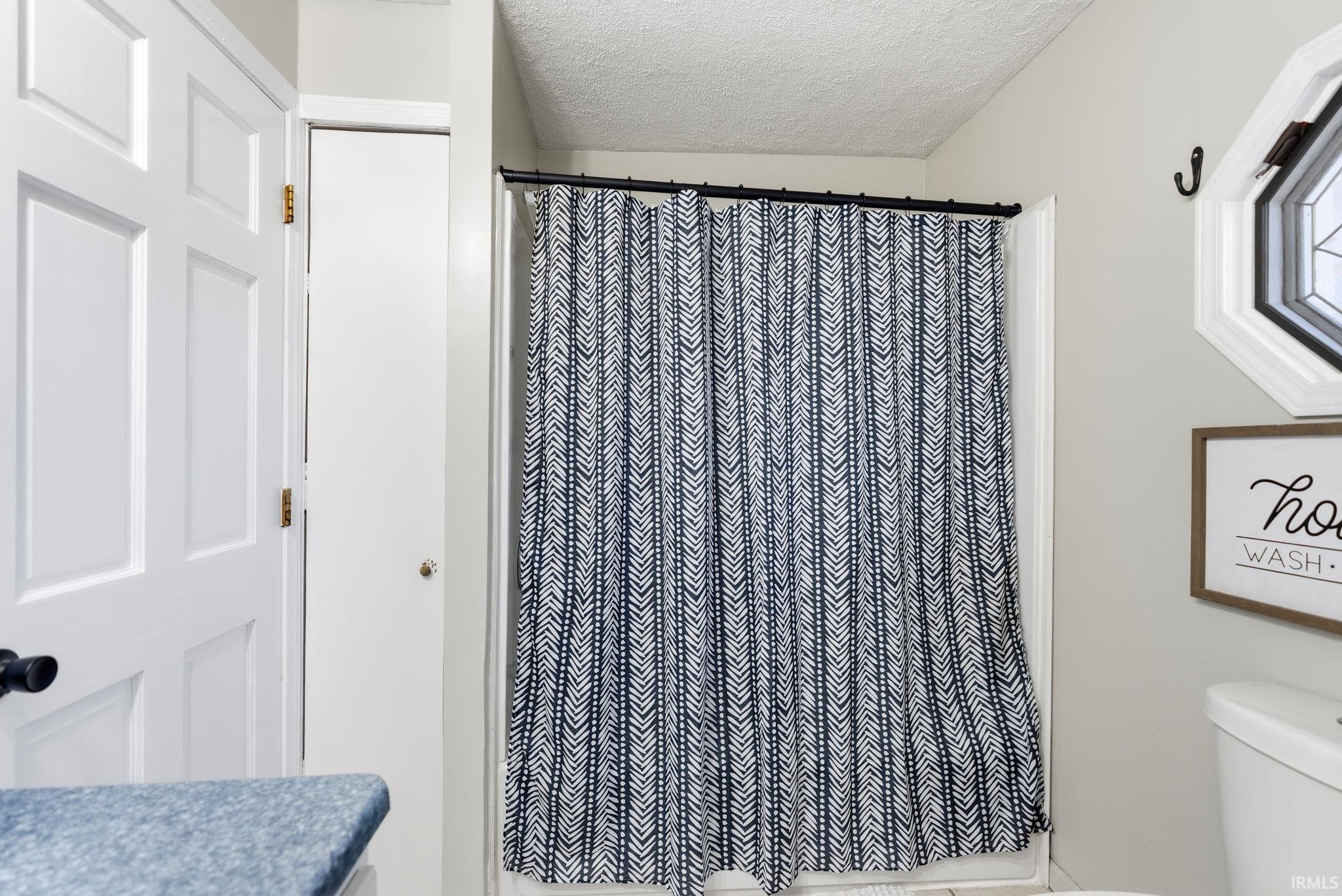 Full bathroom featuring a shower with curtain and a textured ceiling