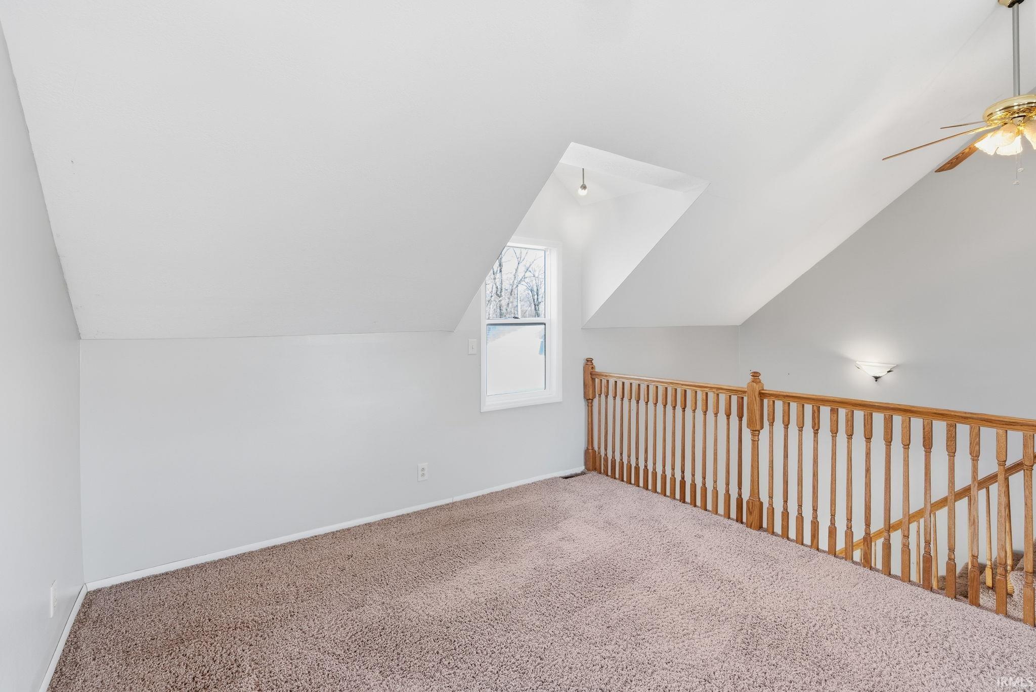 Additional living space with vaulted ceiling, ceiling fan, and carpet flooring