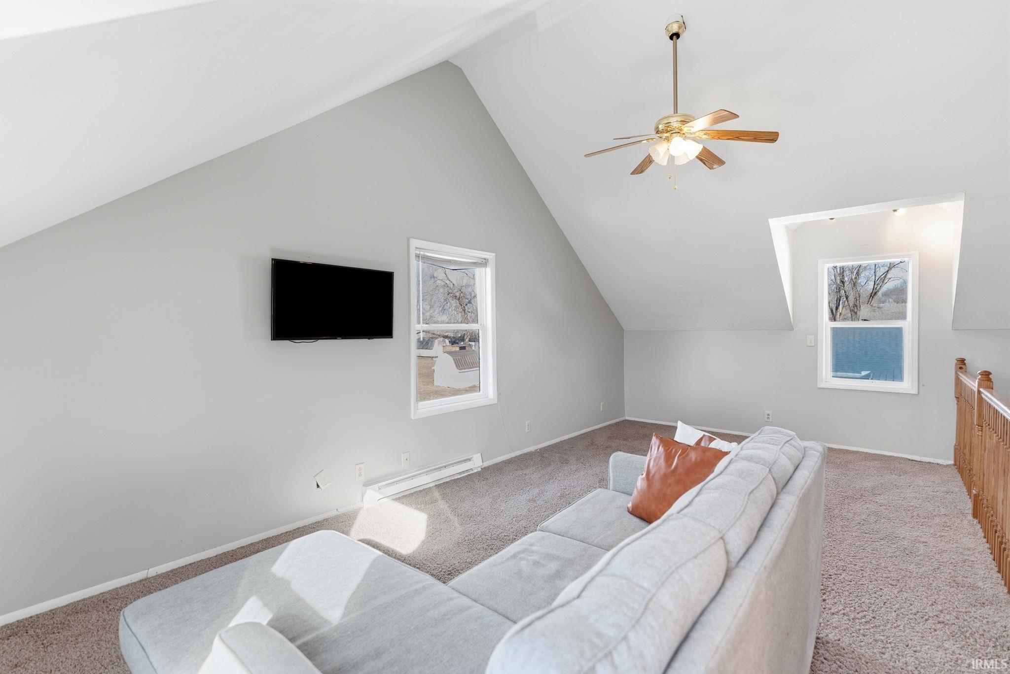 Living area featuring carpet flooring, a baseboard radiator, and ceiling fan