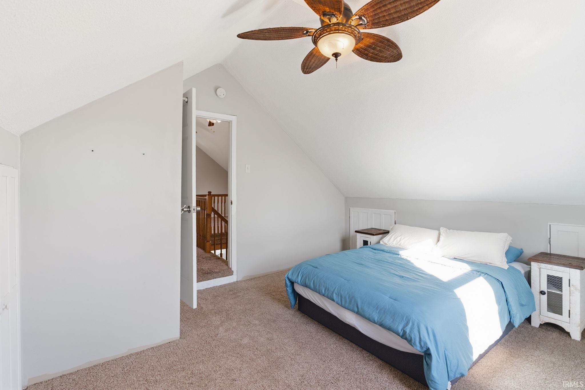 Carpeted bedroom featuring lofted ceiling and ceiling fan