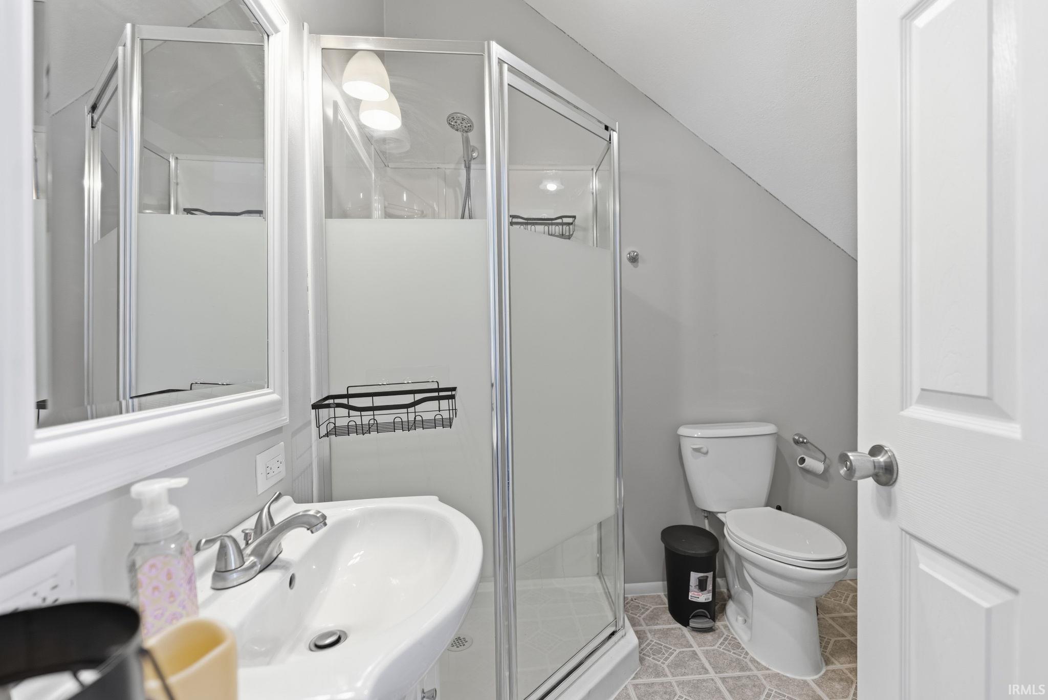 Bathroom with a stall shower, light tile patterned floors, and lofted ceiling