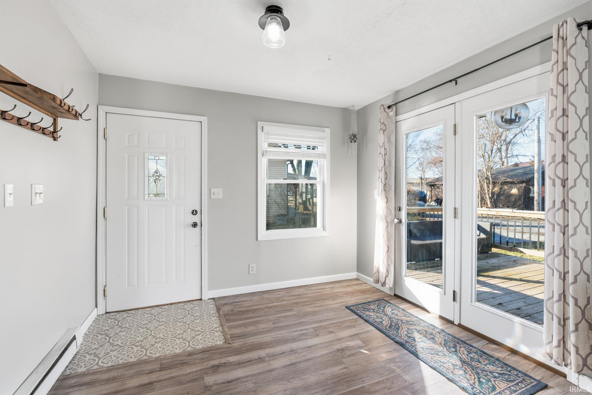Entrance foyer featuring baseboard heating, wood finished floors, and plenty of natural light