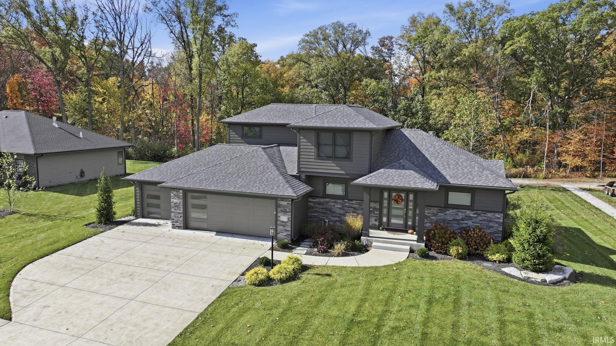 View of front of house with stone siding, a front lawn, and a shingled roof
