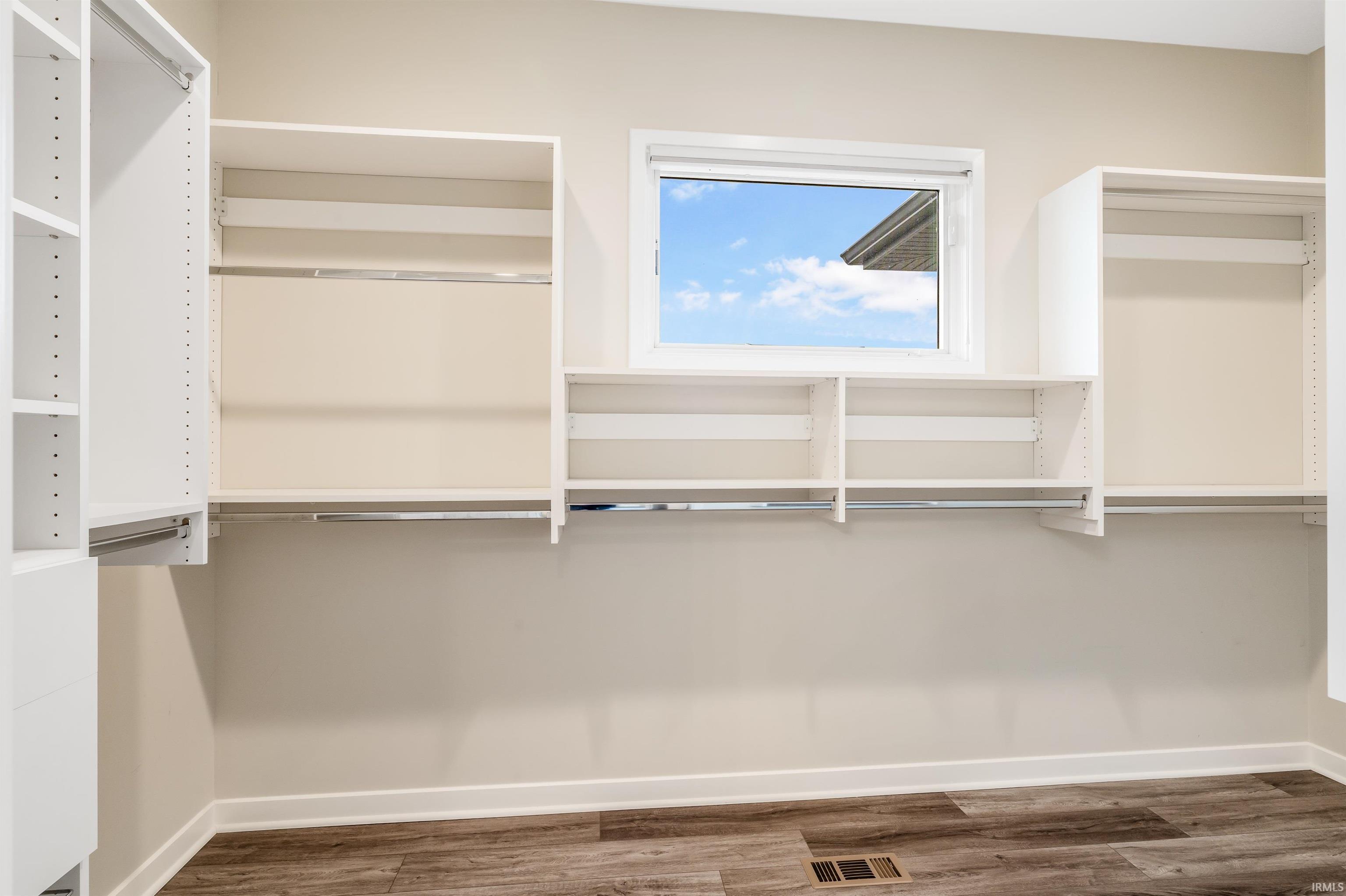 Walk in closet with dark wood-style floors