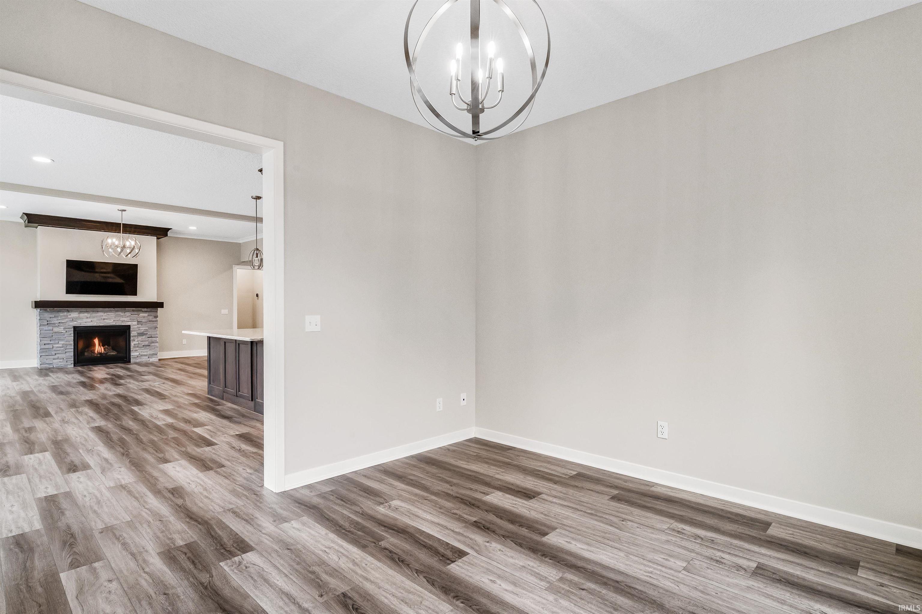 Unfurnished dining area with hanging lights, wood finished floors, and a stone fireplace