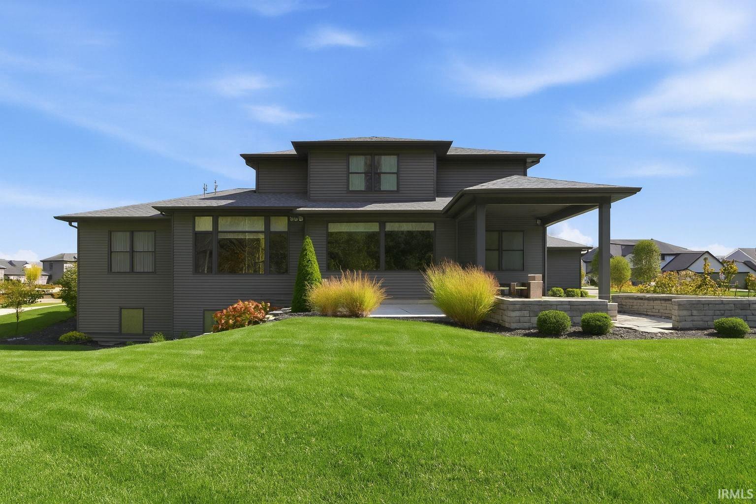 Rear view of property with a patio, a yard, and a shingled roof