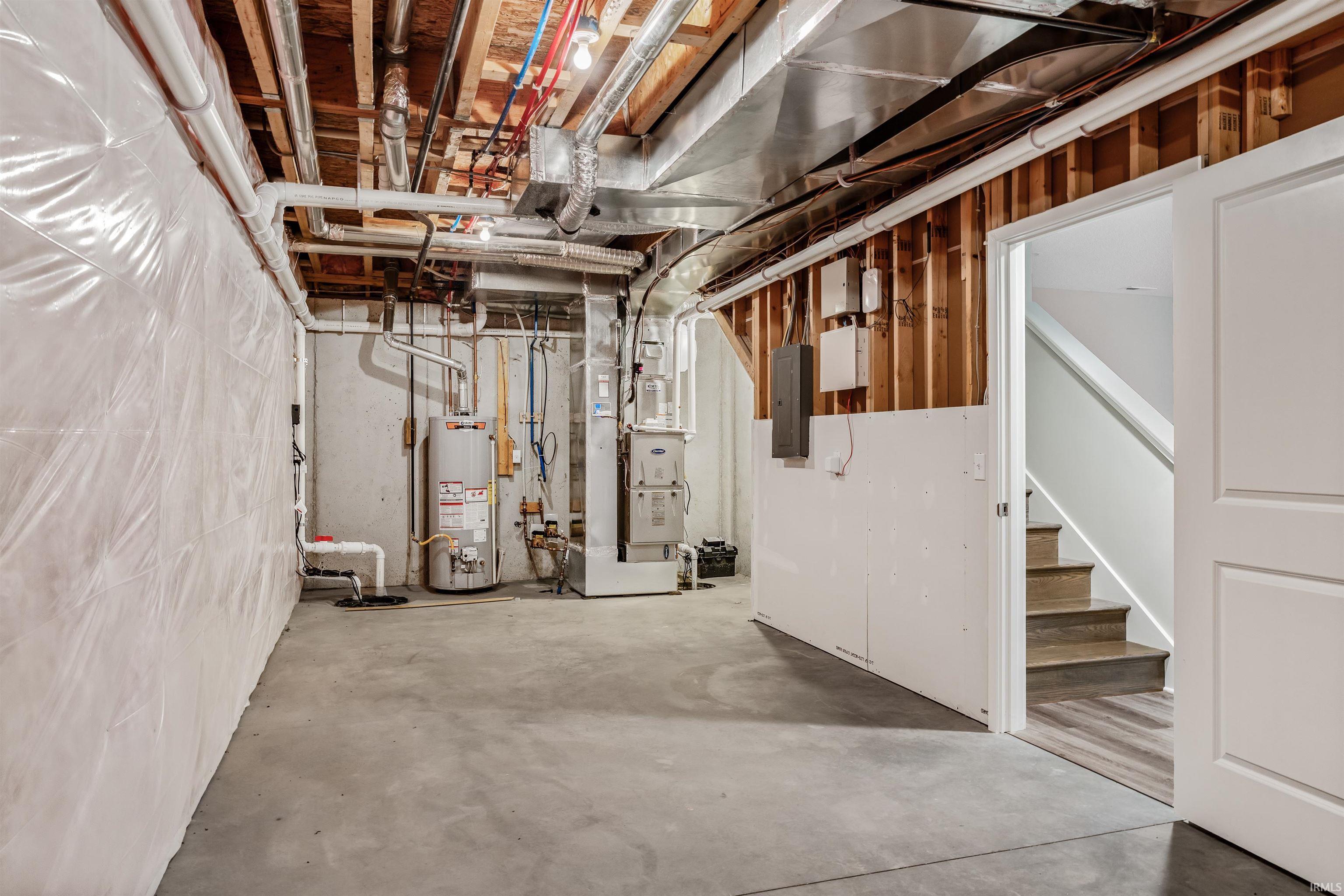 Unfinished basement with water heater, heating unit, and electric panel