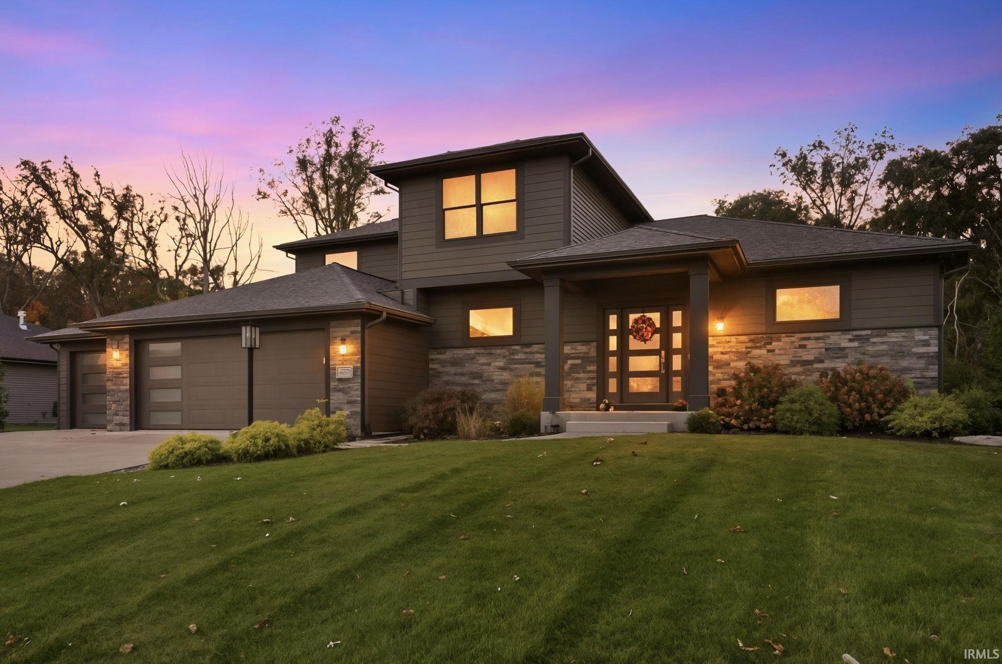View of front of house featuring stone siding, a garage, a front yard, and driveway