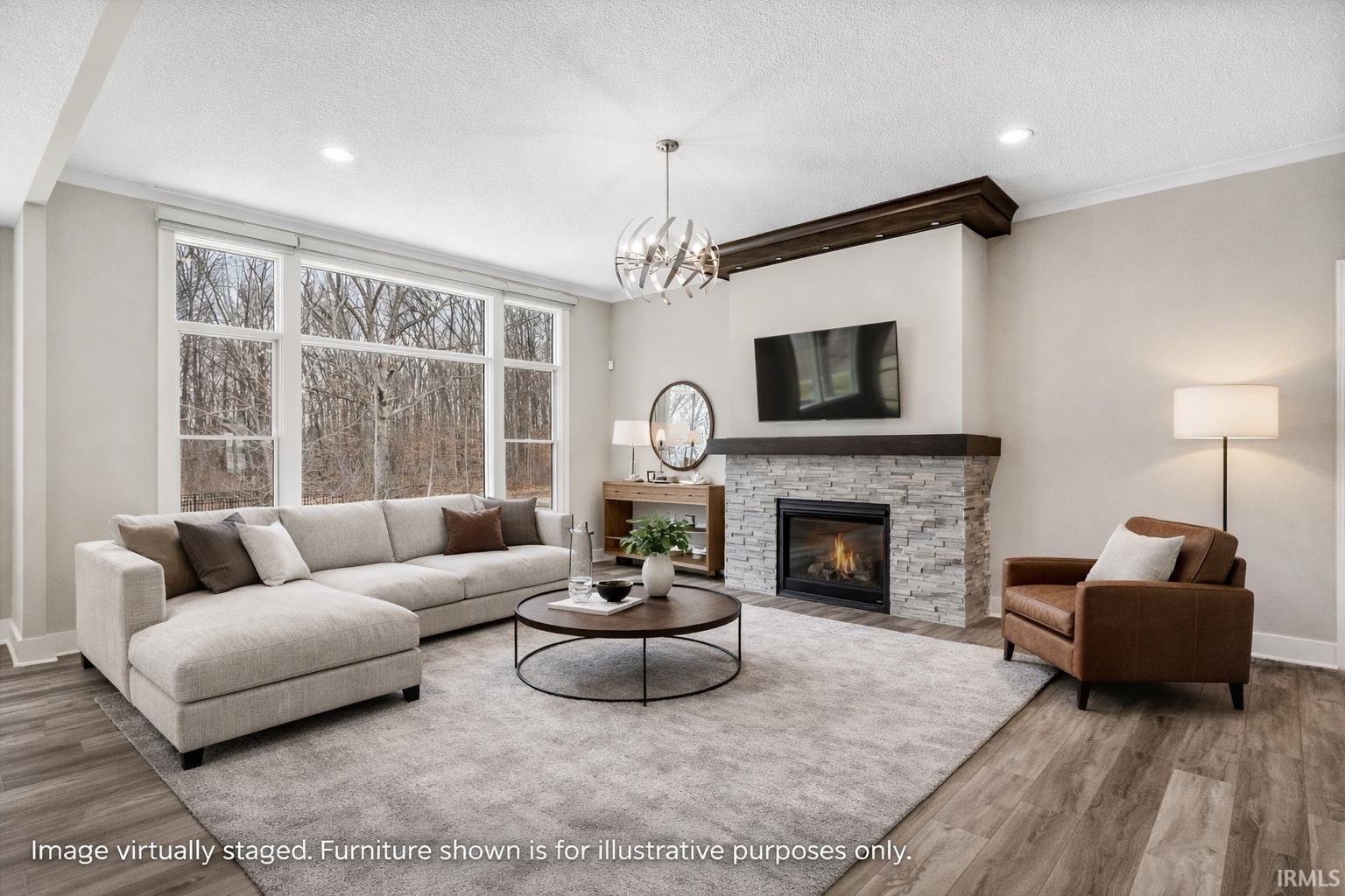 Living area with wood finished floors, a stone fireplace, suspended lighting, a textured ceiling, and ornamental molding