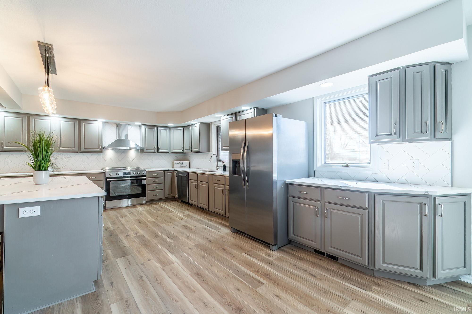 Kitchen featuring gray cabinets, decorative backsplash, and stainless steel appliances