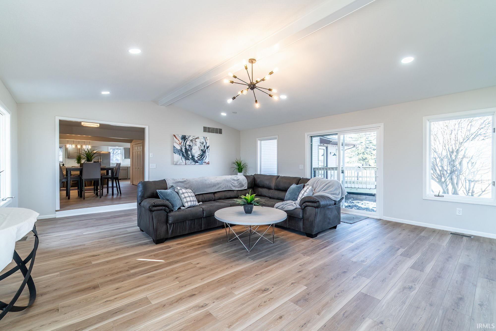 Living area with beam ceiling, light wood-type flooring, and hanging lights