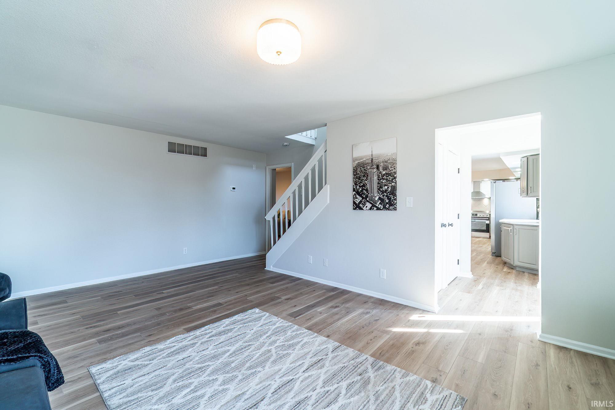 Unfurnished living room with stairway and light wood-style floors