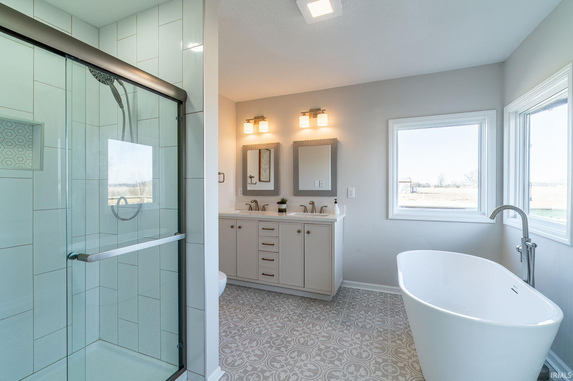 Bathroom featuring a soaking tub, double vanity, and a shower stall