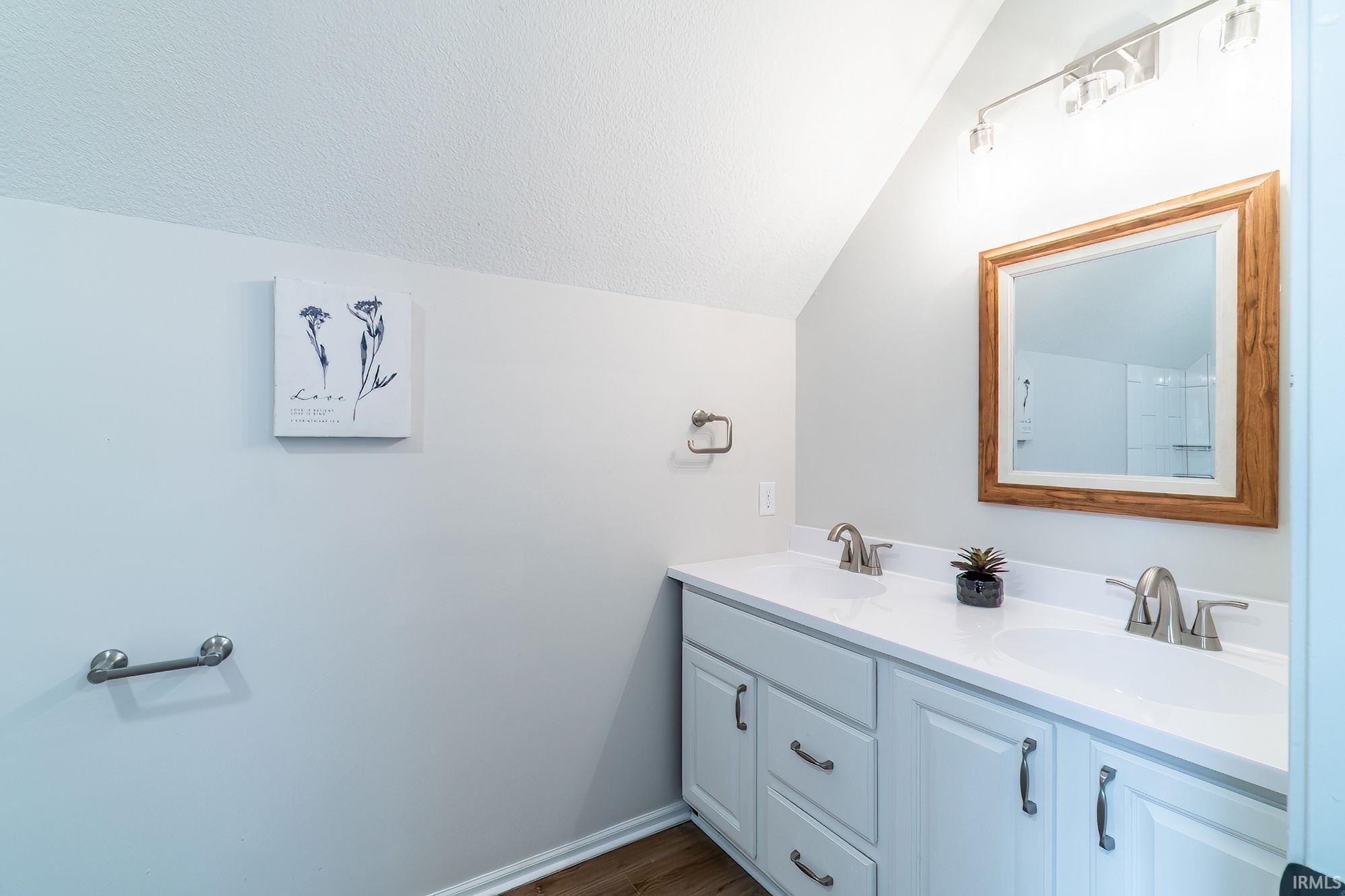 Bathroom featuring double vanity and dark wood finished floors