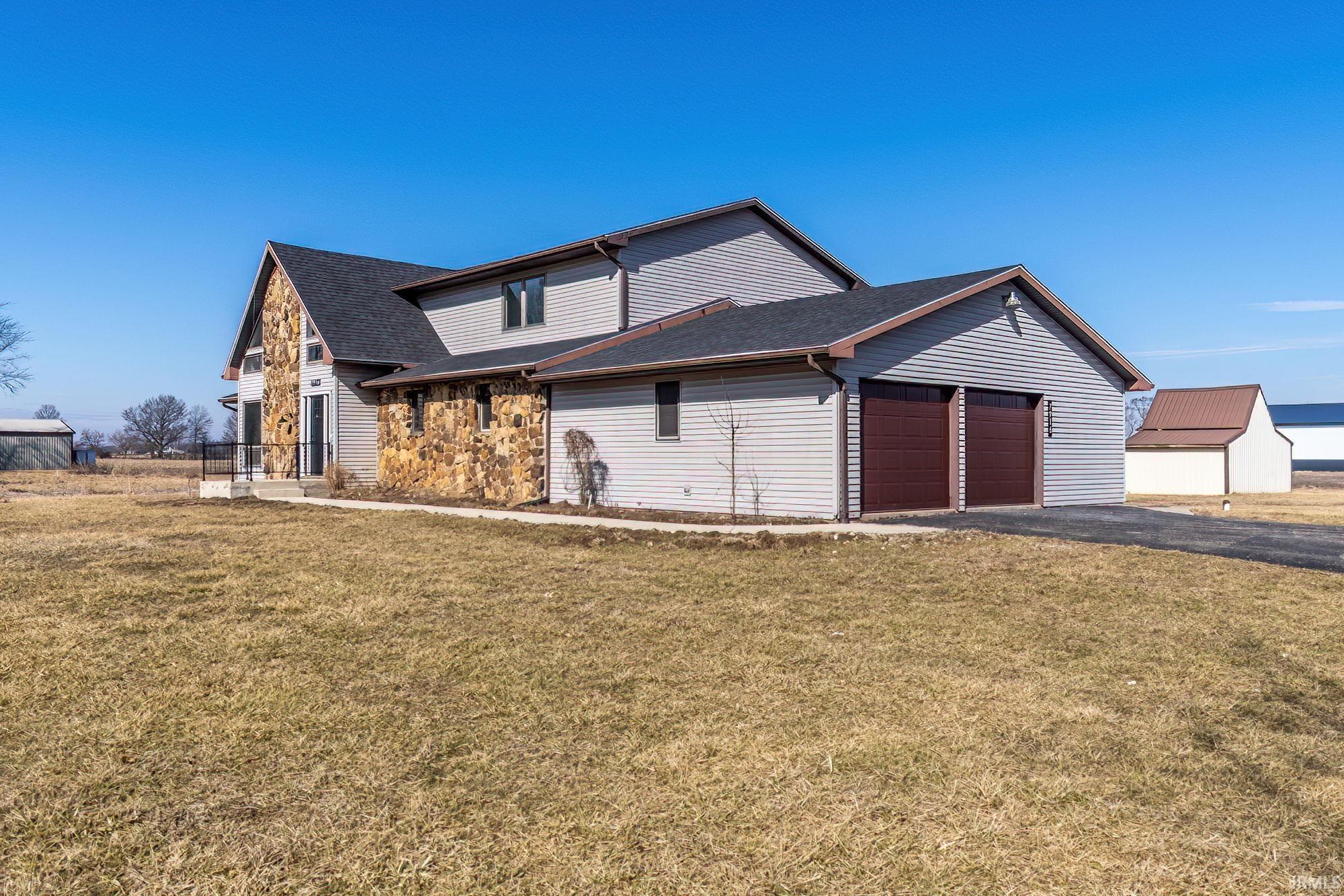 View of front of property featuring a garage, a front yard, asphalt driveway, stone siding, and a shingled roof