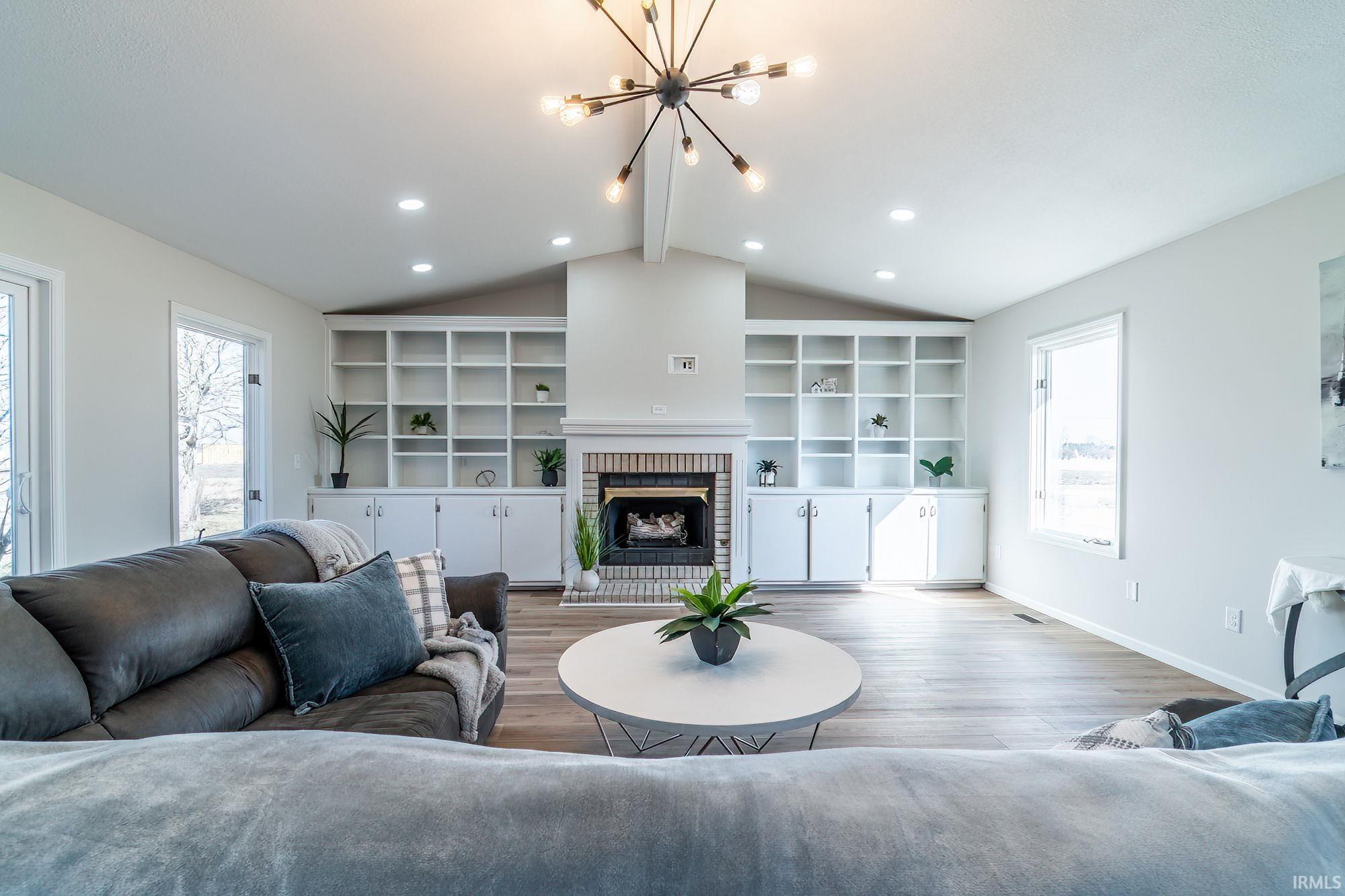 Living room featuring wood finished floors, suspended lighting, and a fireplace